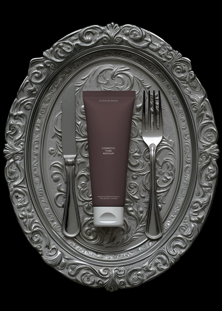Tube of cream on a decorative silver platter with a fork and knife