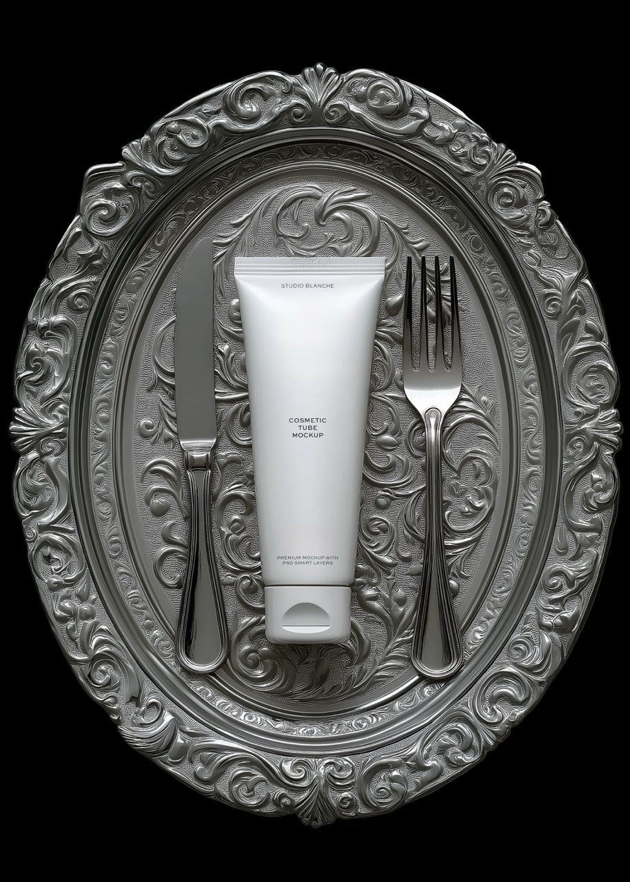 Tube of cream on a decorative silver plate with a fork and knife