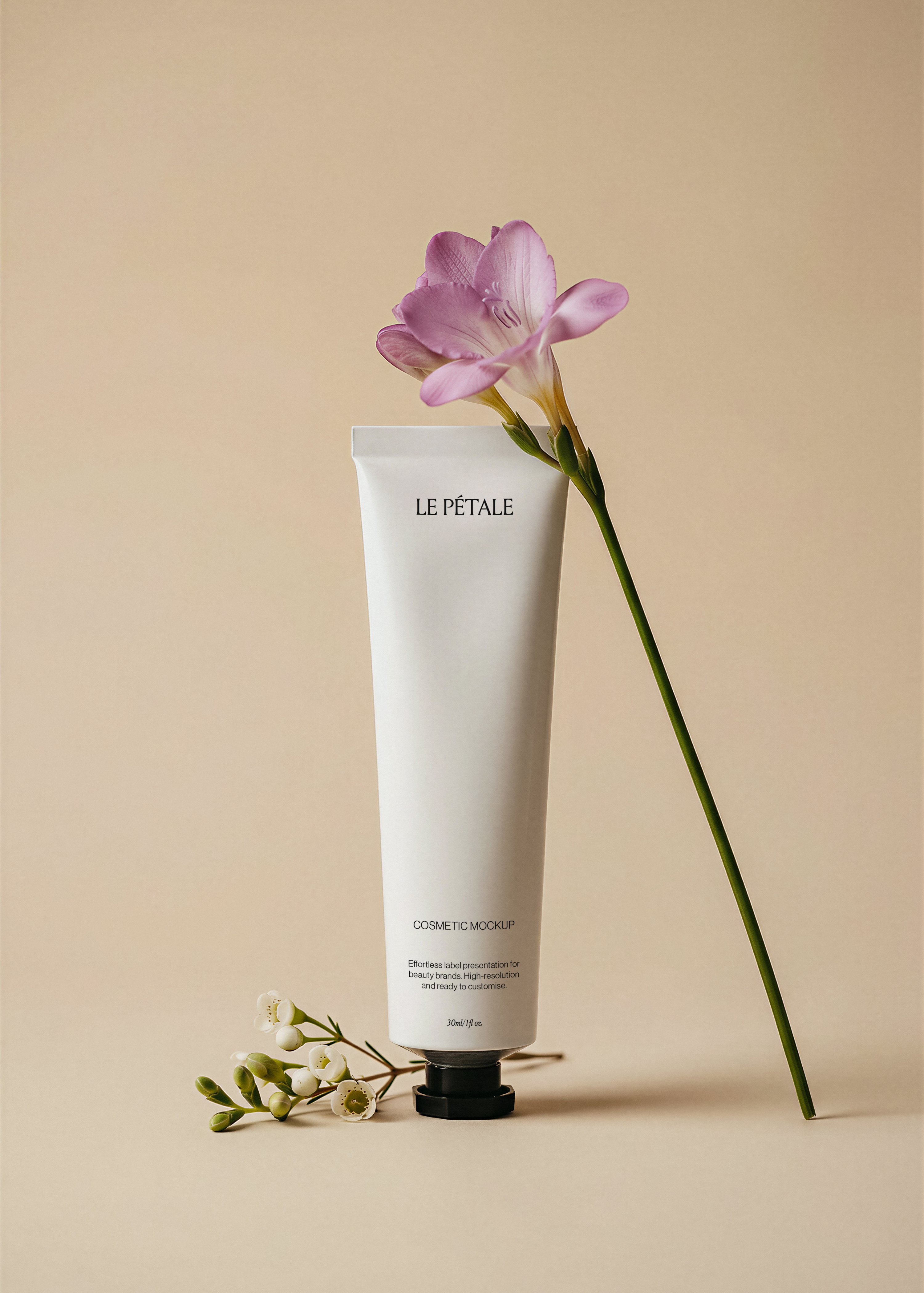 White cosmetic tube mockup with label, lilac freesia stem alongside, wax flower sprig at base, warm sand backdrop