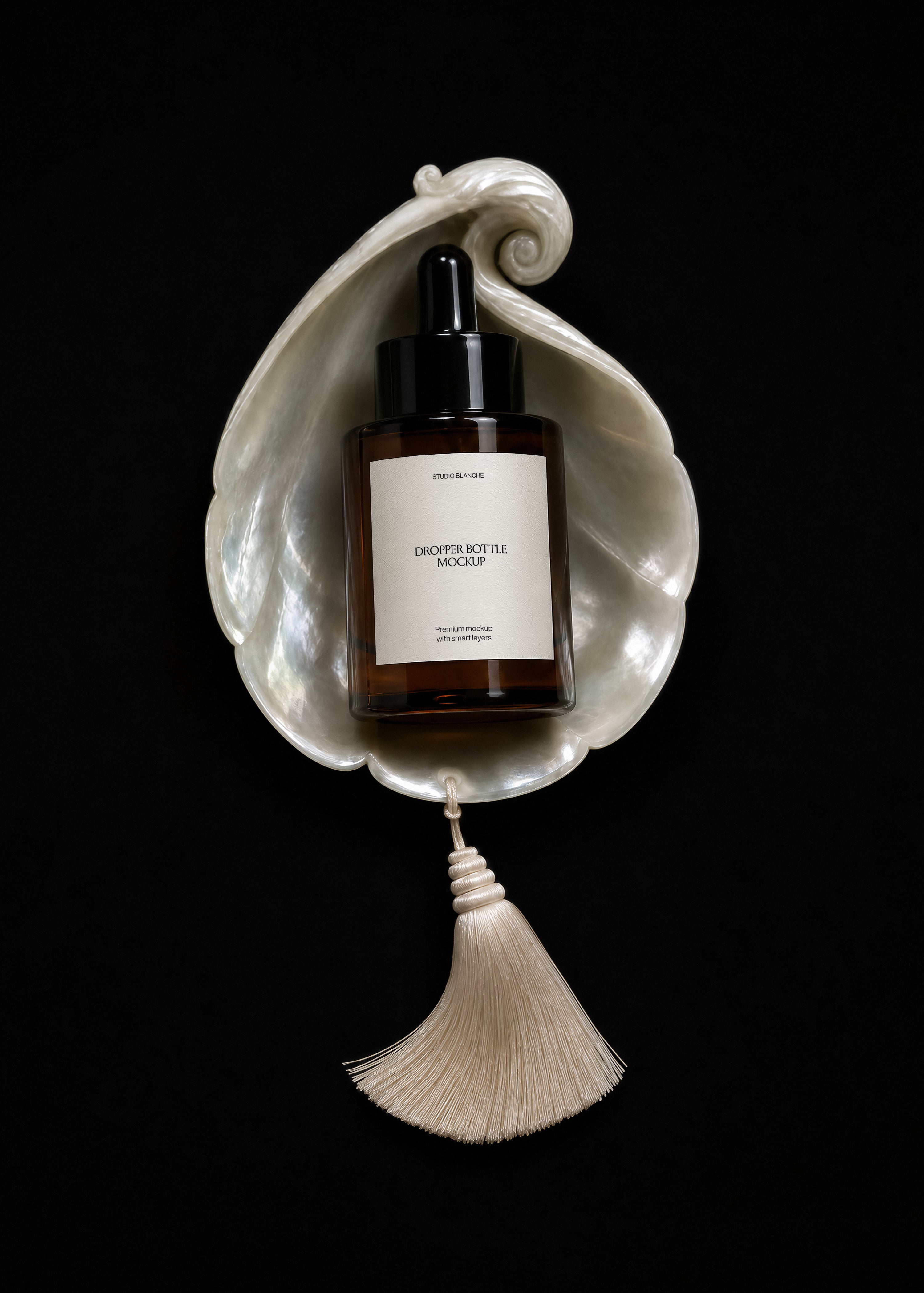Dropper bottle mockup on iridescent shell, white label shown upright, cream tassel below, dark editorial styling