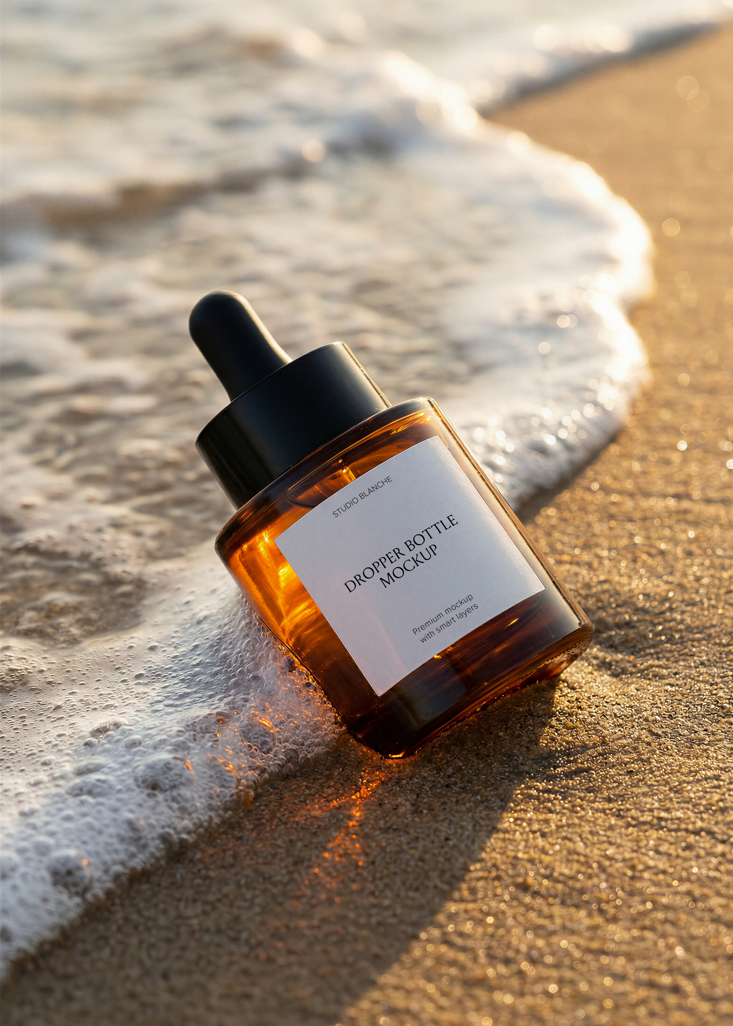 Amber glass serum dropper bottle mockup at the shoreline, foam lapping the sand, black pipette top, editorial styling