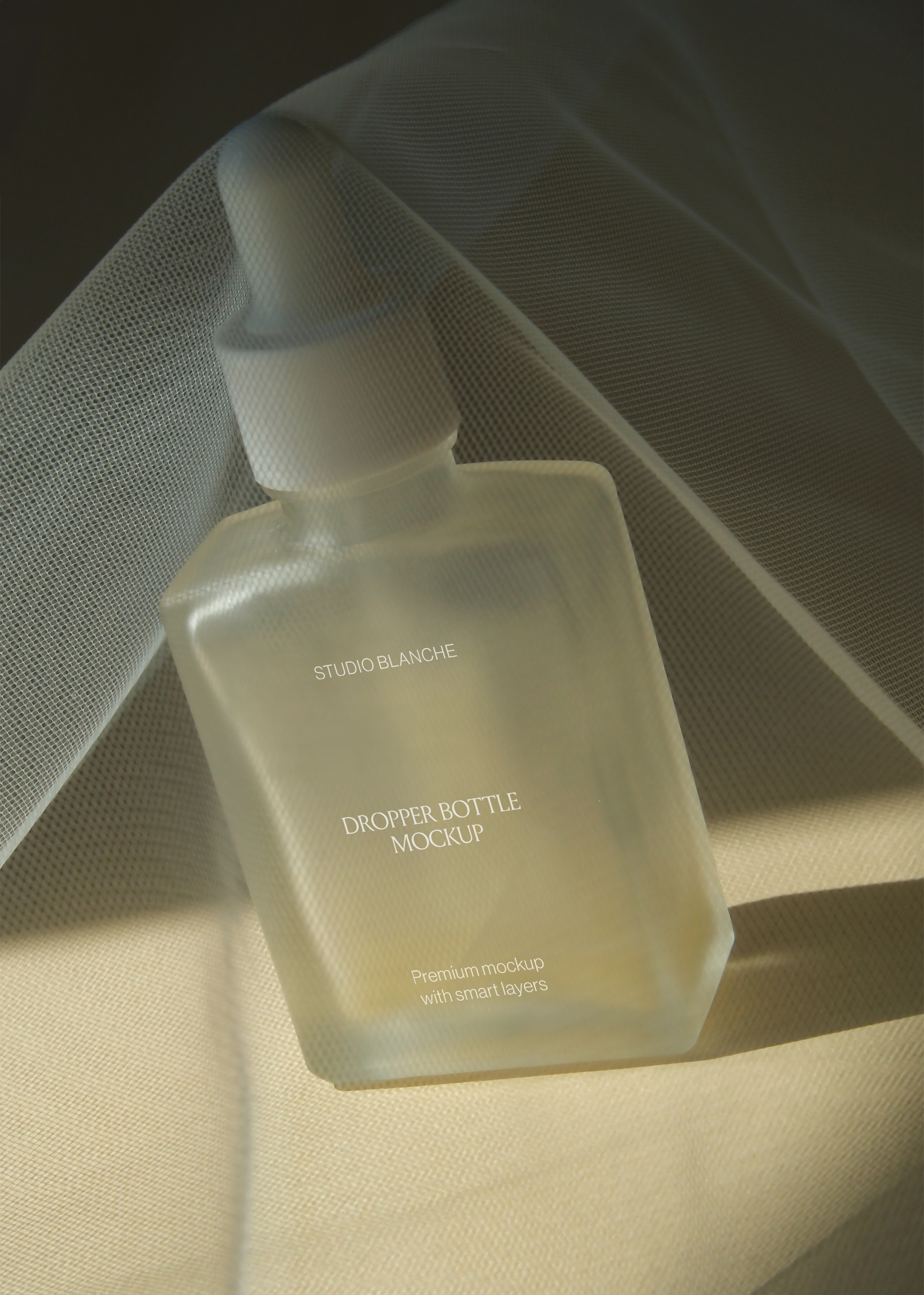 Close angle of frosted rectangular dropper bottle draped in tulle netting, golden warm light, soft focus