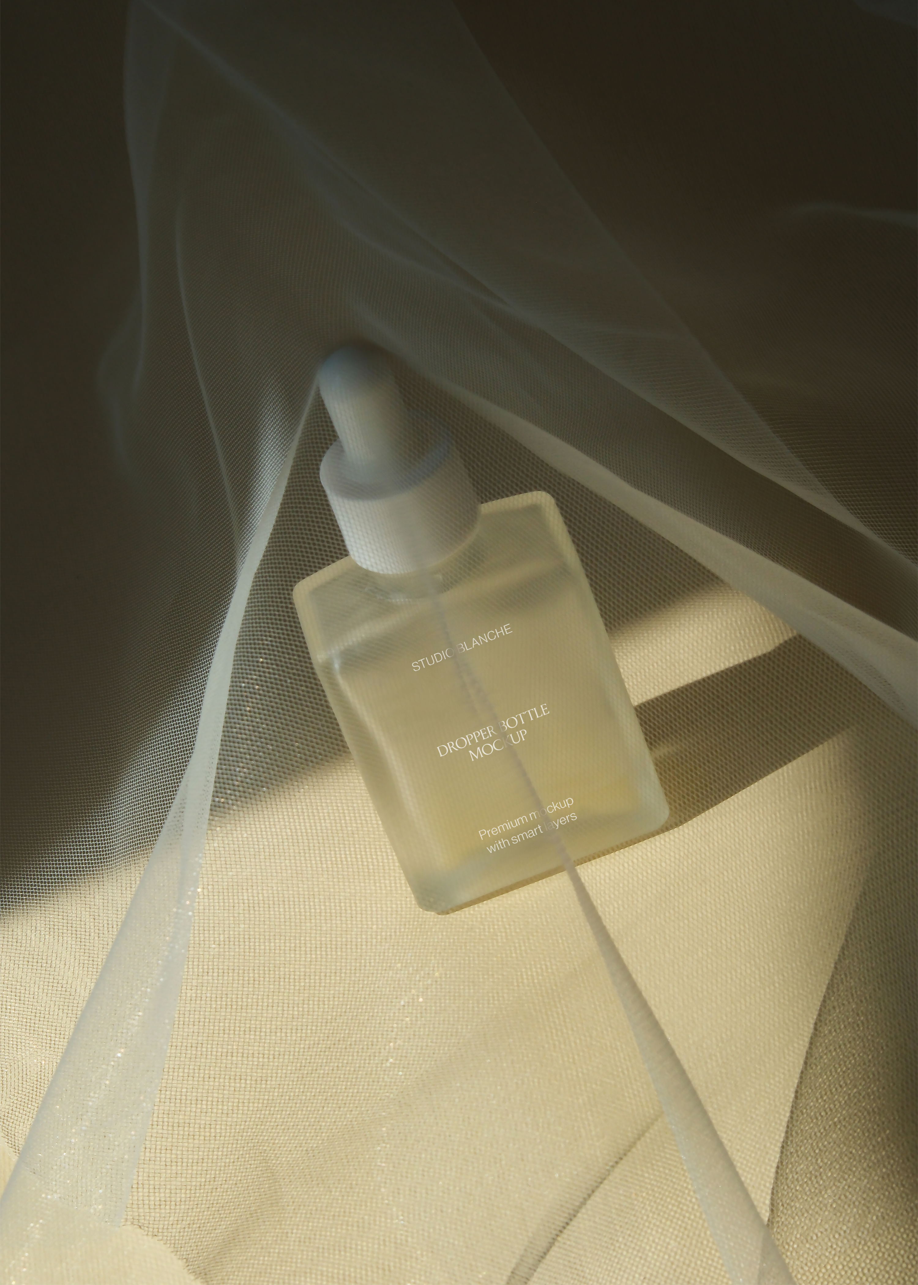 Frosted dropper bottle mockup in shadow under tulle drape, narrow strip of warm light crossing the label