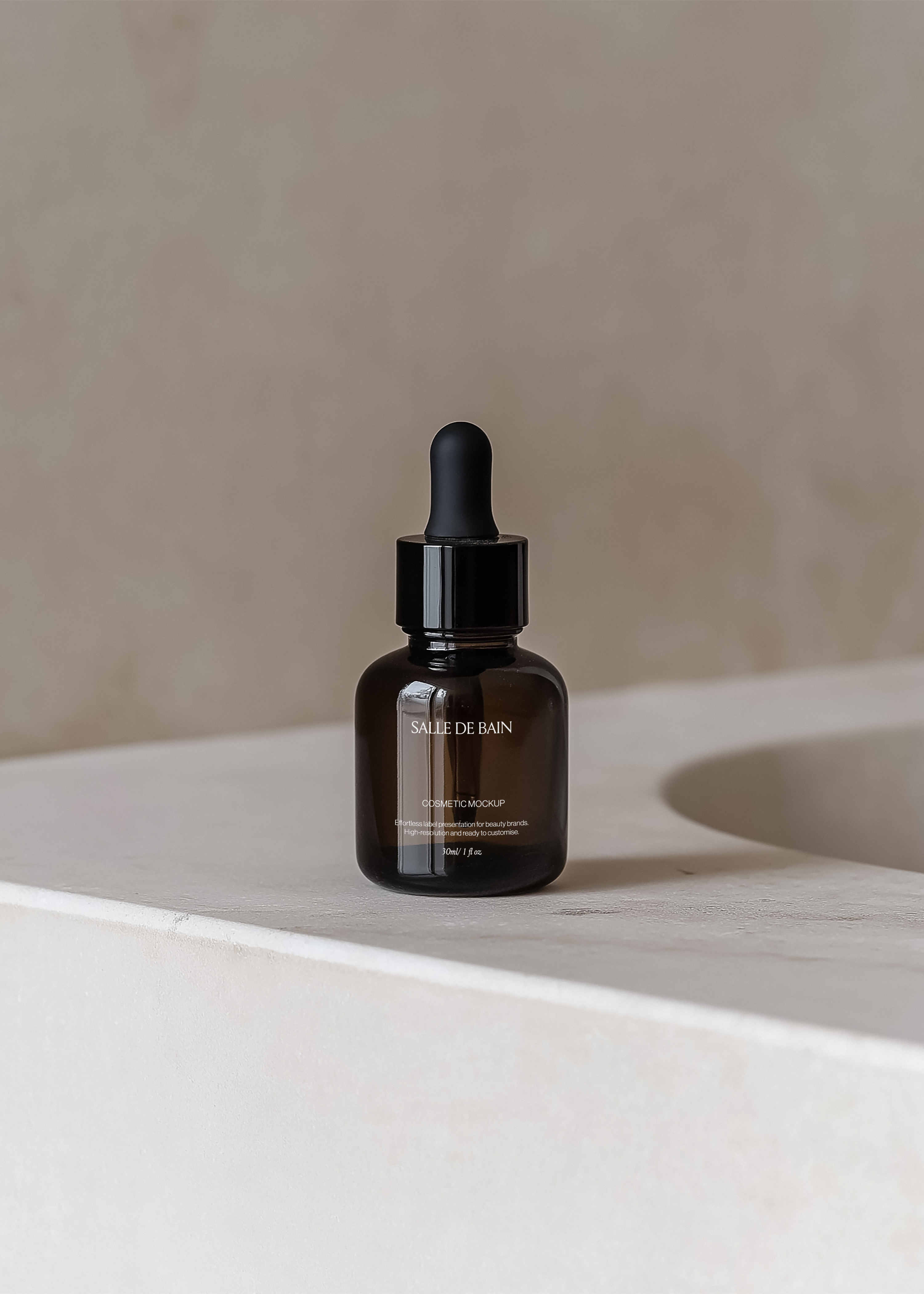 Amber glass dropper bottle mockup with black cap on pale stone basin ledge, soft shadow and warm plaster wall behind
