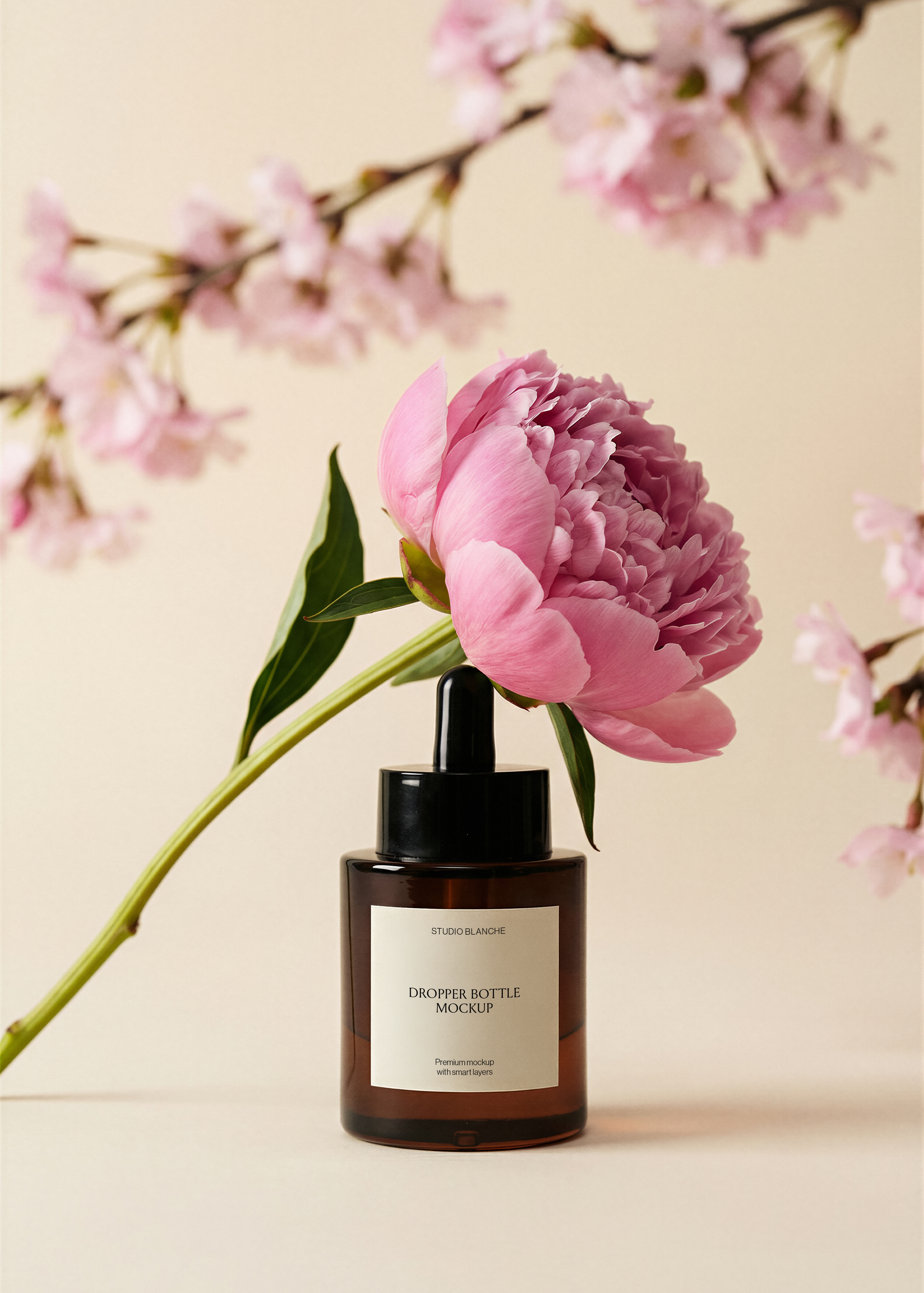 Amber dropper bottle mockup showing label area, full pink peony and stem, cherry blossom branches crossing background, beige surface