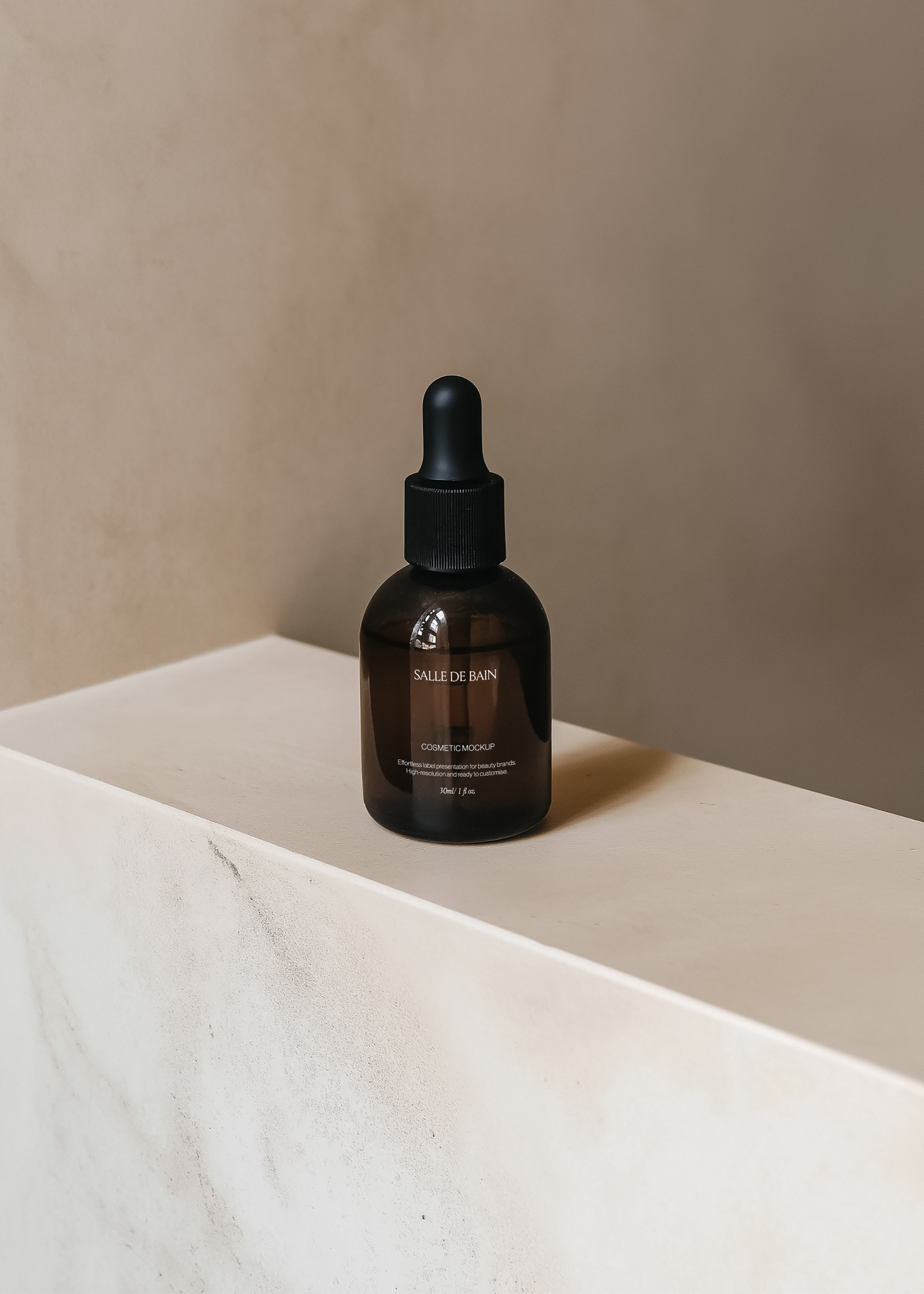 Dark amber dropper bottle mockup with black cap on pale stone plinth corner, warm plaster wall and directional shadow