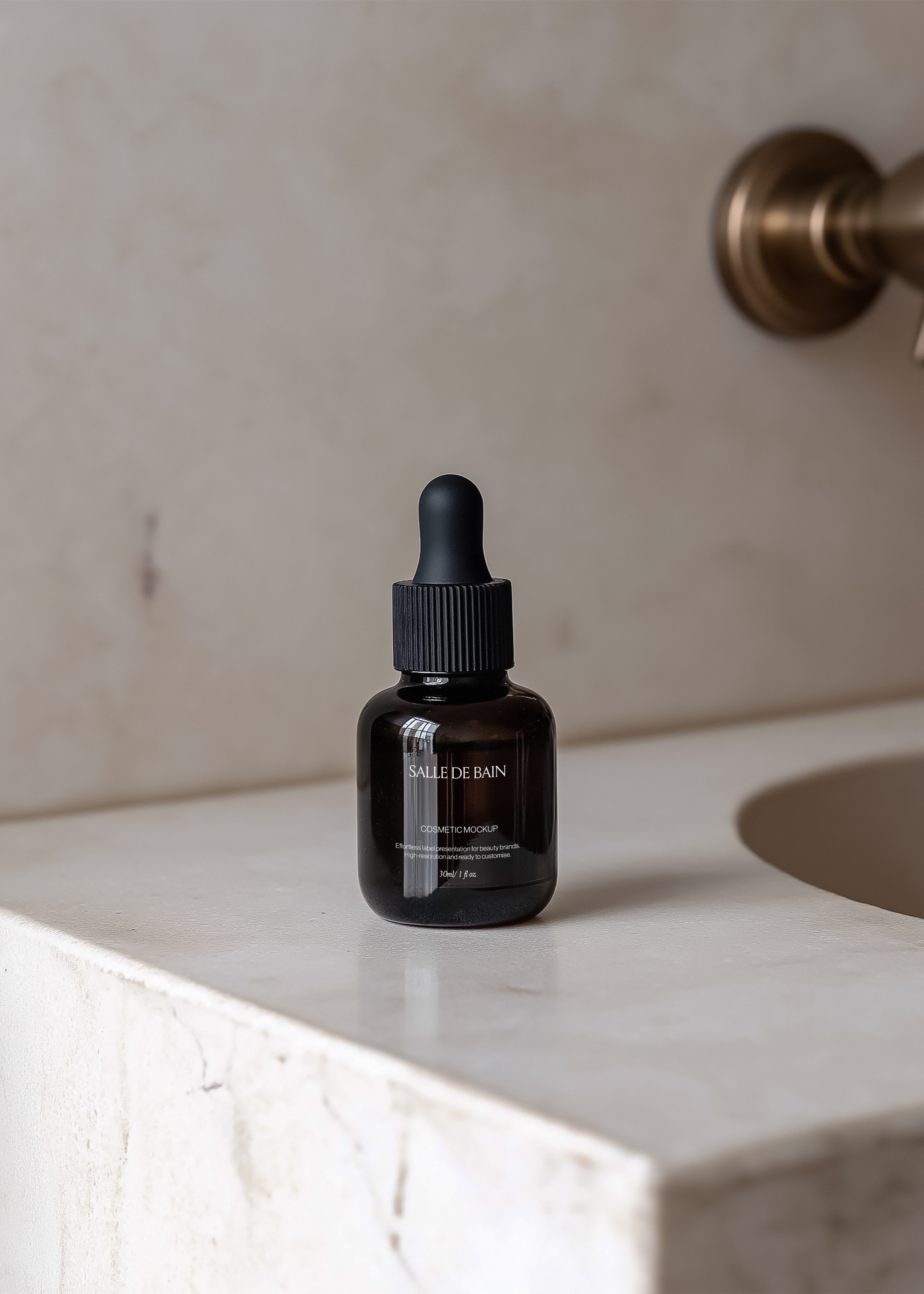 Amber glass dropper bottle mockup on polished marble ledge, blurred brass wall tap behind, warm minimal bathroom scene