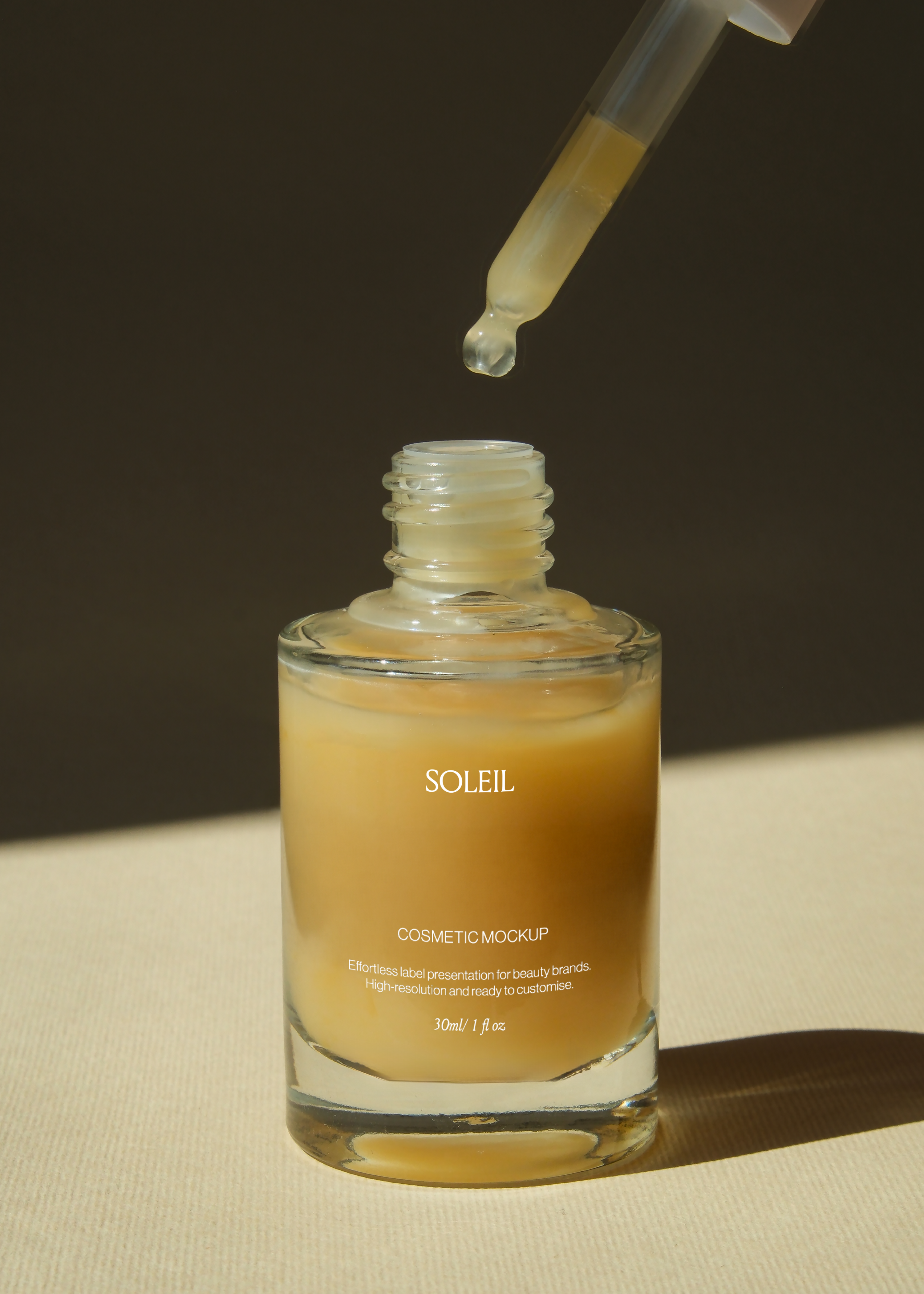 Glass dropper bottle mockup with amber serum drop suspended above open neck, warm sunlit tabletop, dark backdrop
