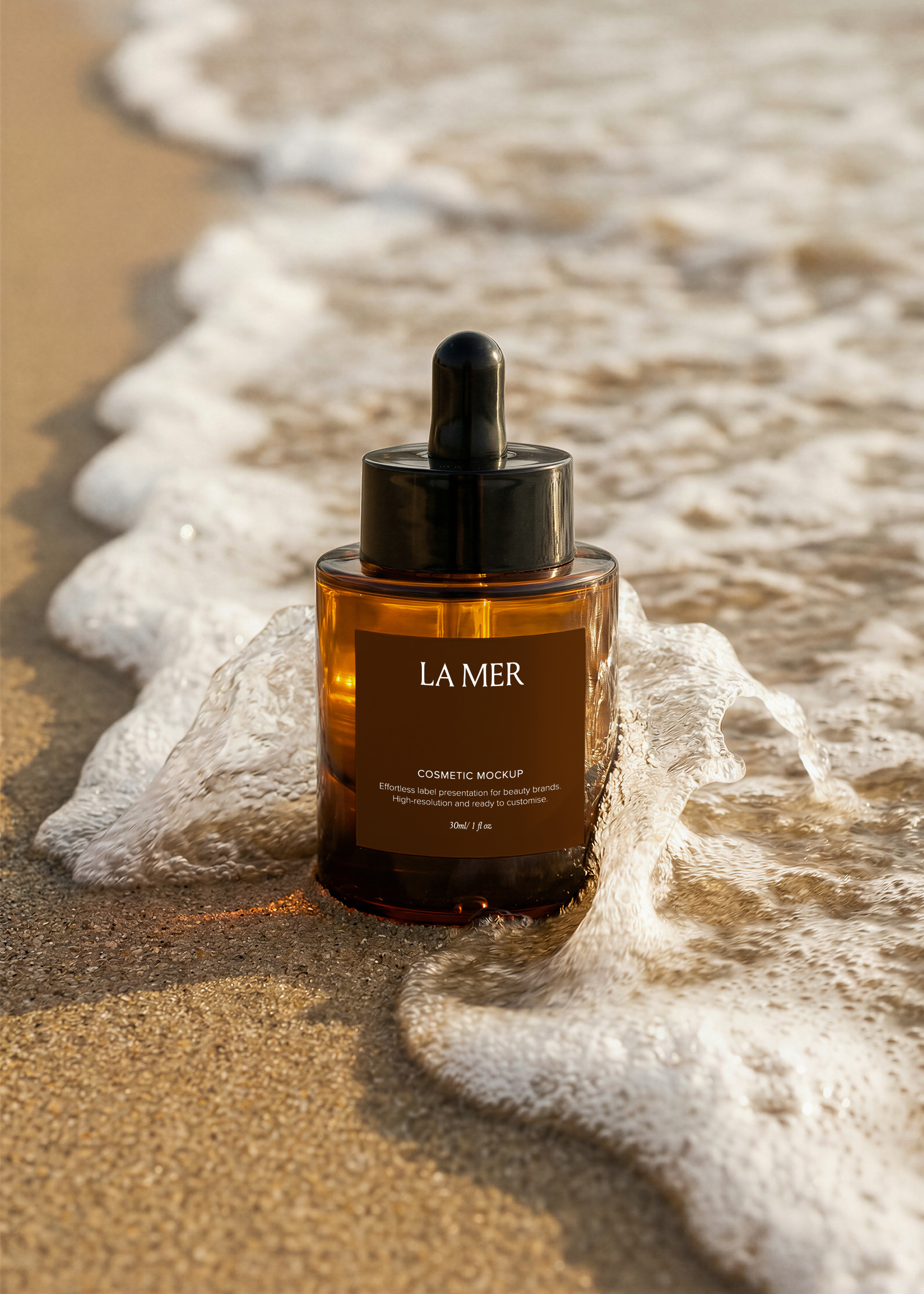 Amber dropper bottle mockup standing upright on wet sand with sea foam curling around the base, warm golden-hour light