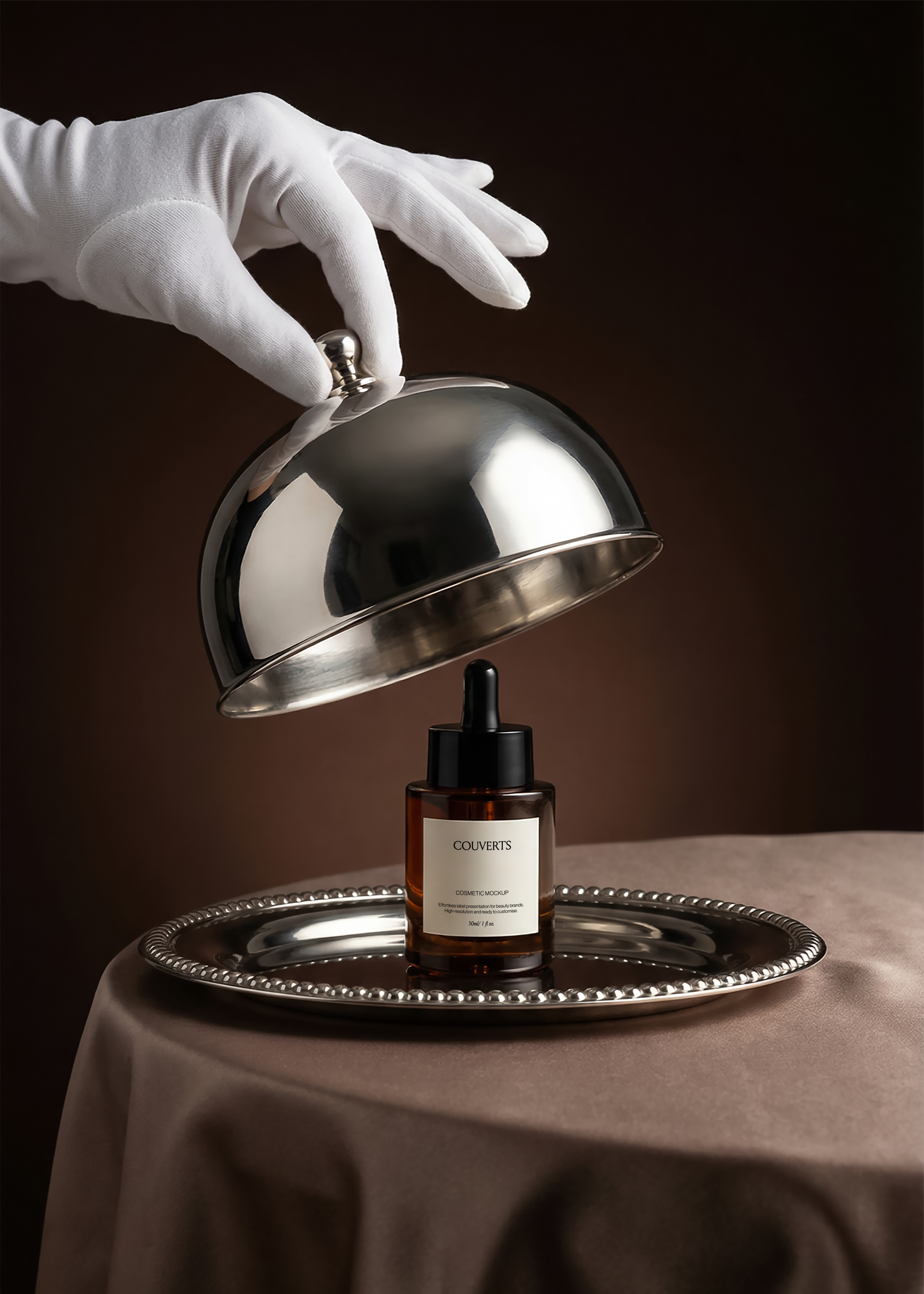 Gloved hand lifting a silver cloche over an amber dropper bottle mockup on a silver tray, dark brown backdrop