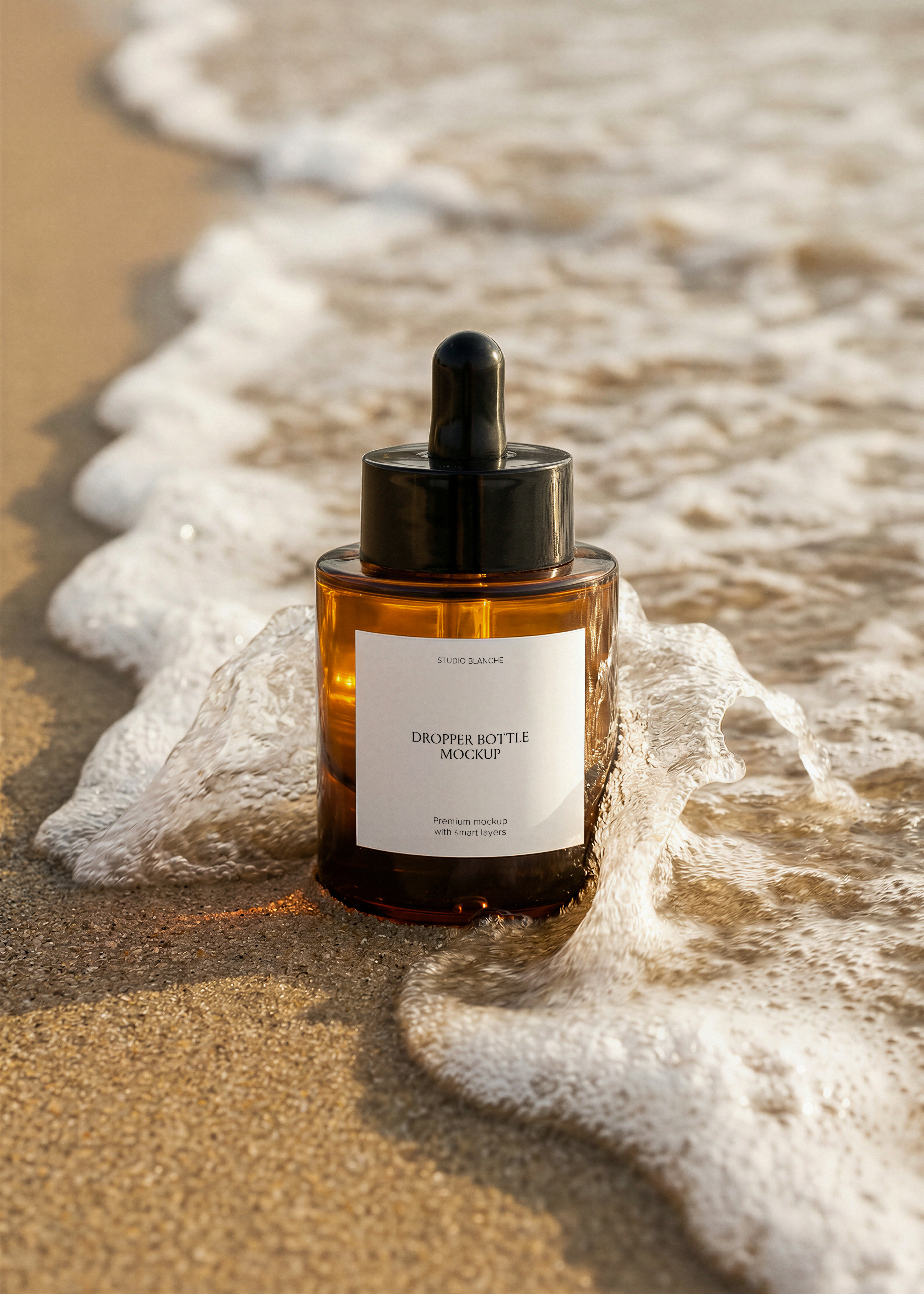 Amber glass serum dropper bottle mockup at the tide line, black pipette cap, foam lapping the shore, editorial styling