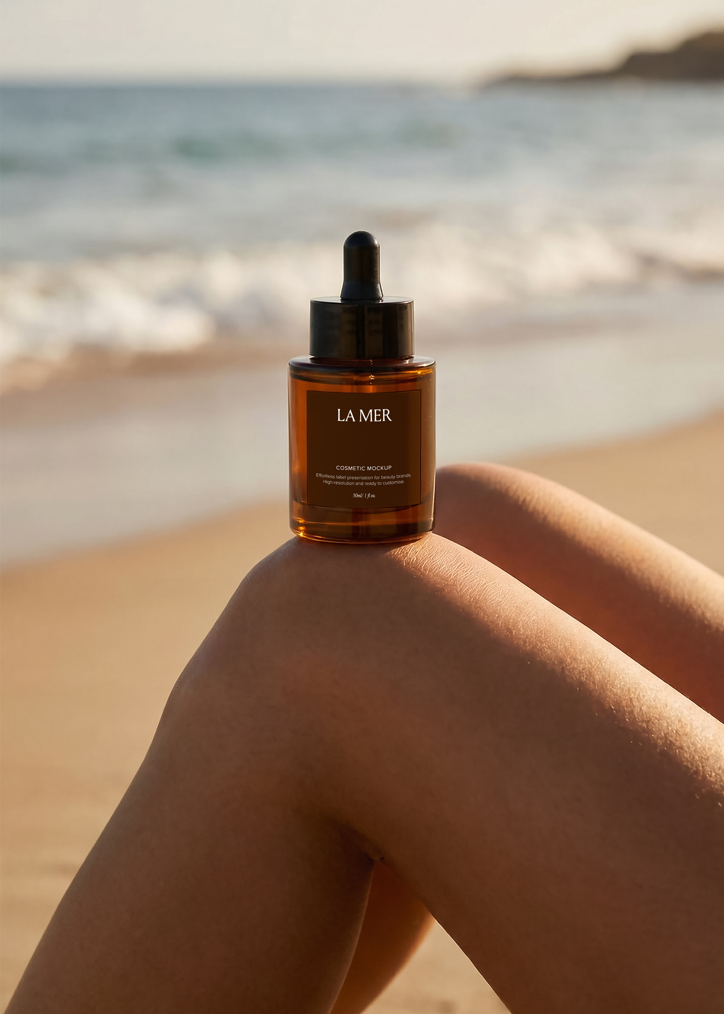 Amber dropper bottle mockup balanced on sun-lit knee with ocean and sandy beach in soft focus behind, warm sunset light