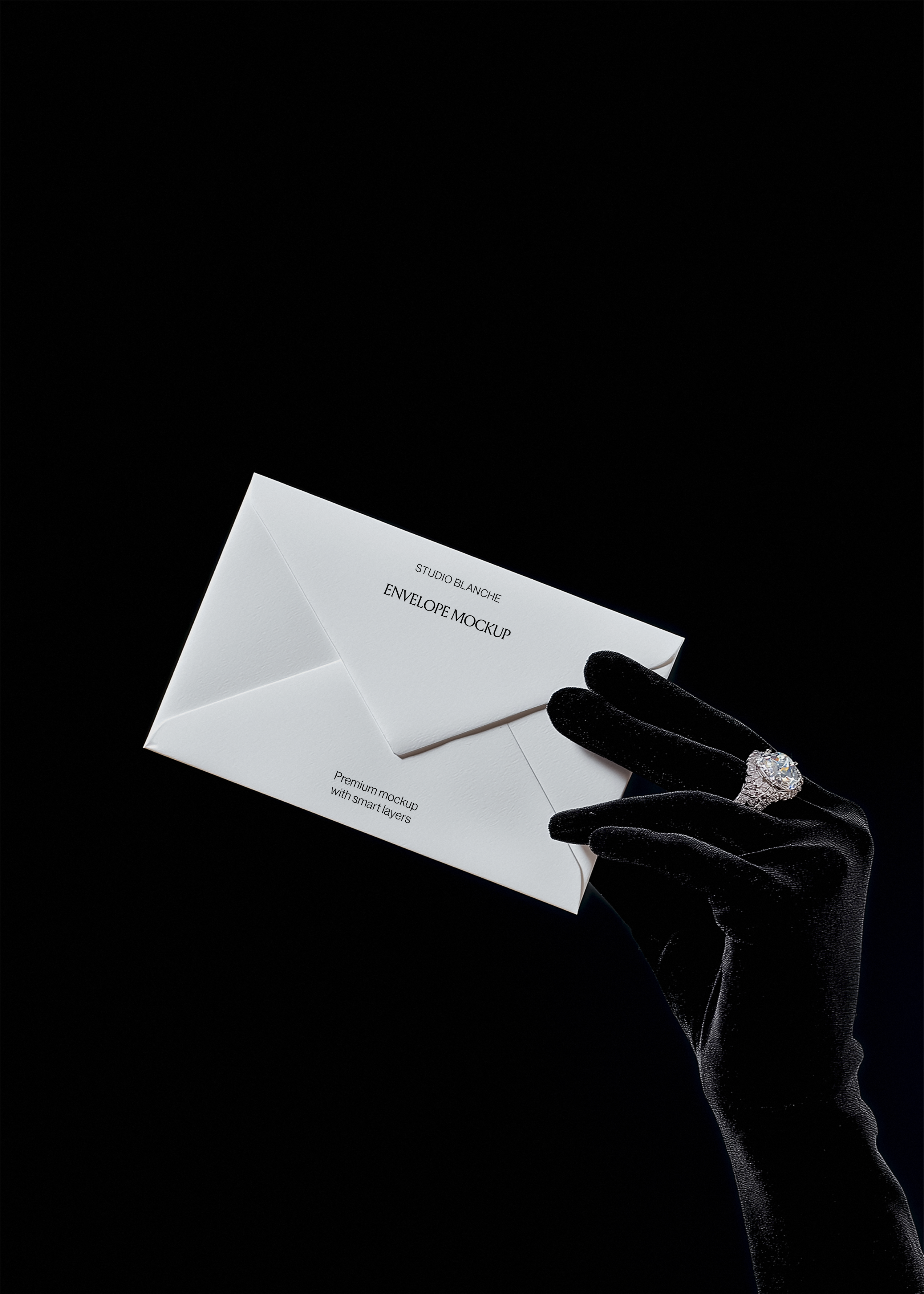Envelope mockup with Studio Blanche wordmark angled against black background, satin glove and diamond ring catching light