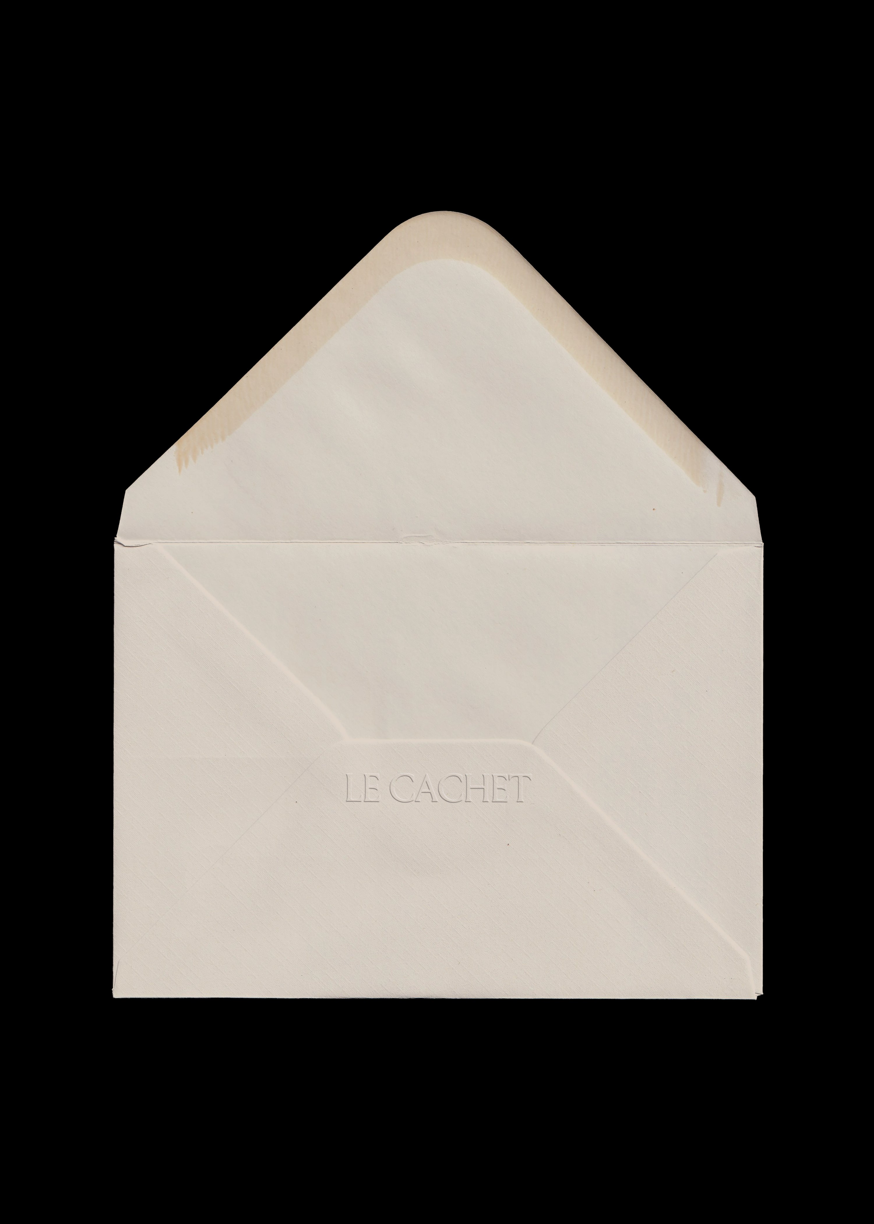 Cream envelope mockup with open triangular flap scanned on black, blind embossed serif wordmark on laid paper