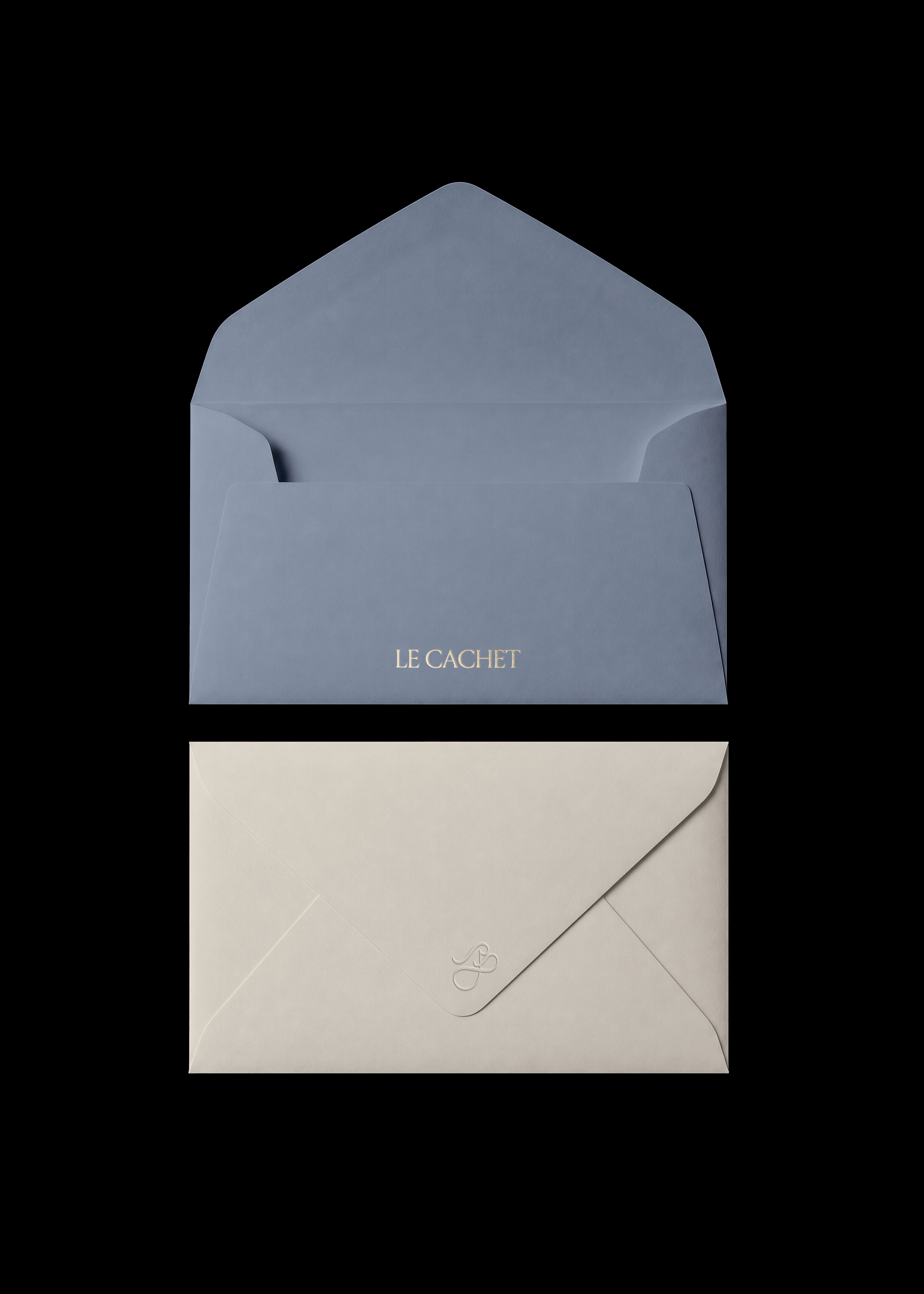 Open slate blue envelope with gold foil wordmark on the flap, cream inner envelope beneath, editorial stationery flat lay
