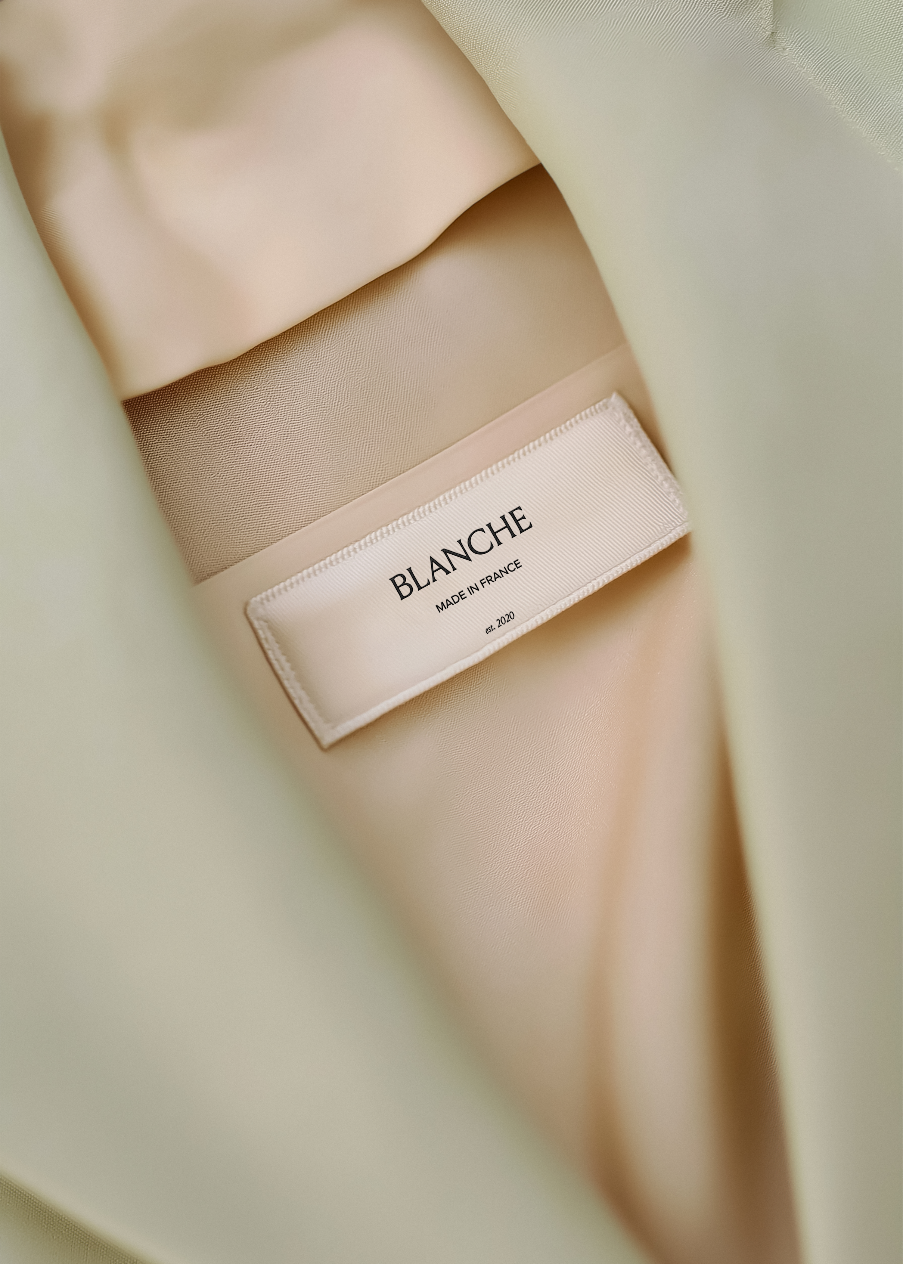 Close-up woven garment label on sage blazer satin lining showing brand name and origin text in serif and sans-serif type