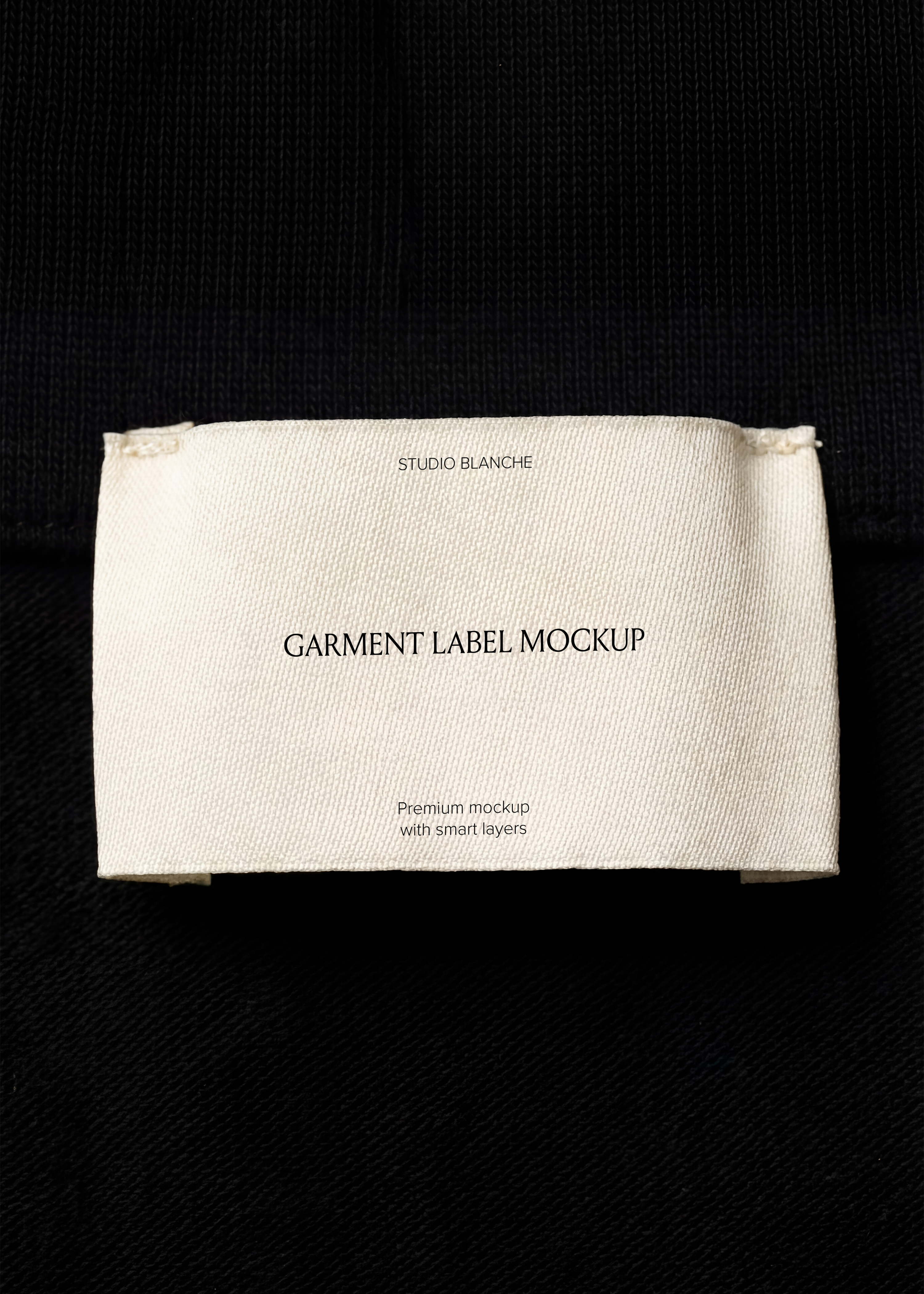 Woven garment label mockup on black jersey collar, archive-style fashion close-up in cream and deep black tones
