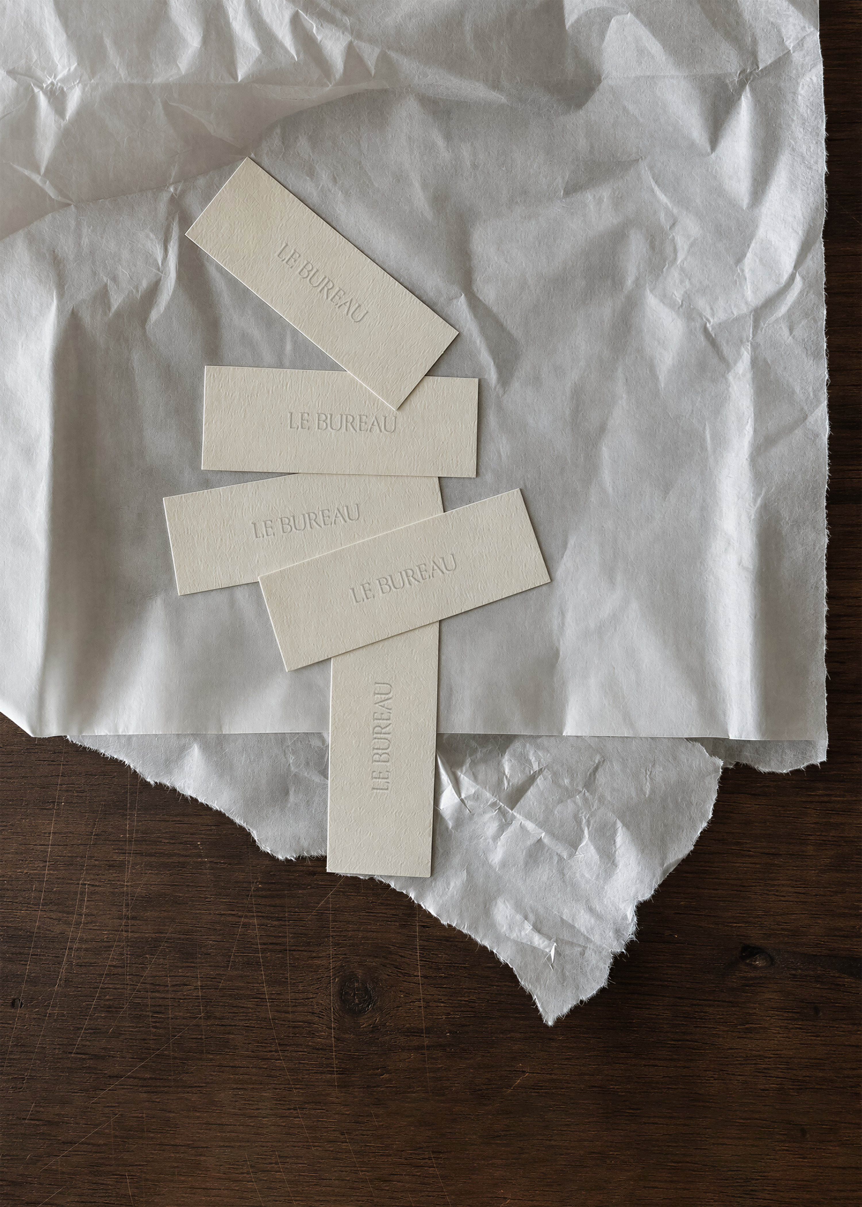 Close view of embossed cream label on textured tissue paper, minimal stationery styling on aged wood