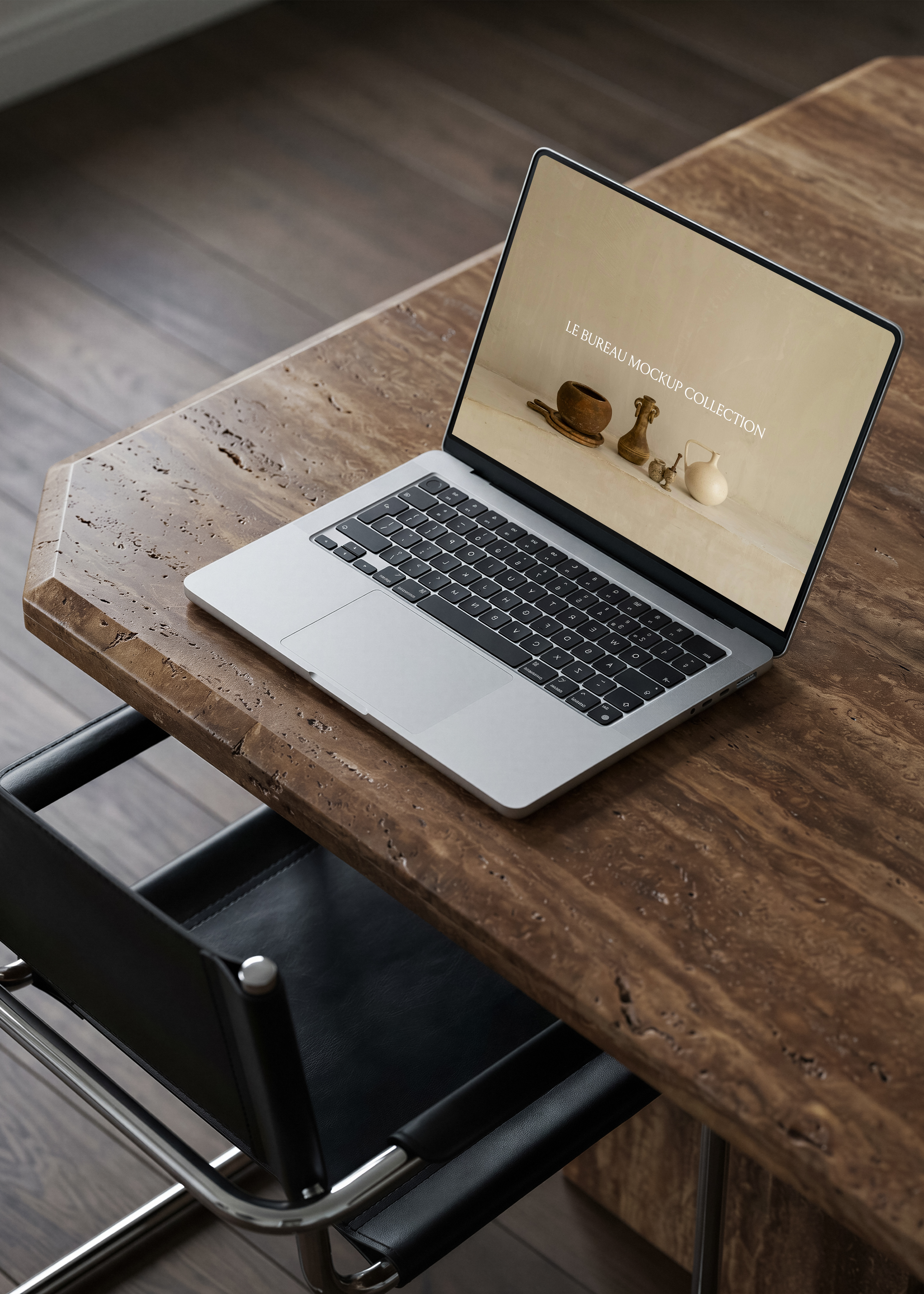 MacBook mockup on travertine desk displaying Le Bureau editorial image, warm architectural office scene