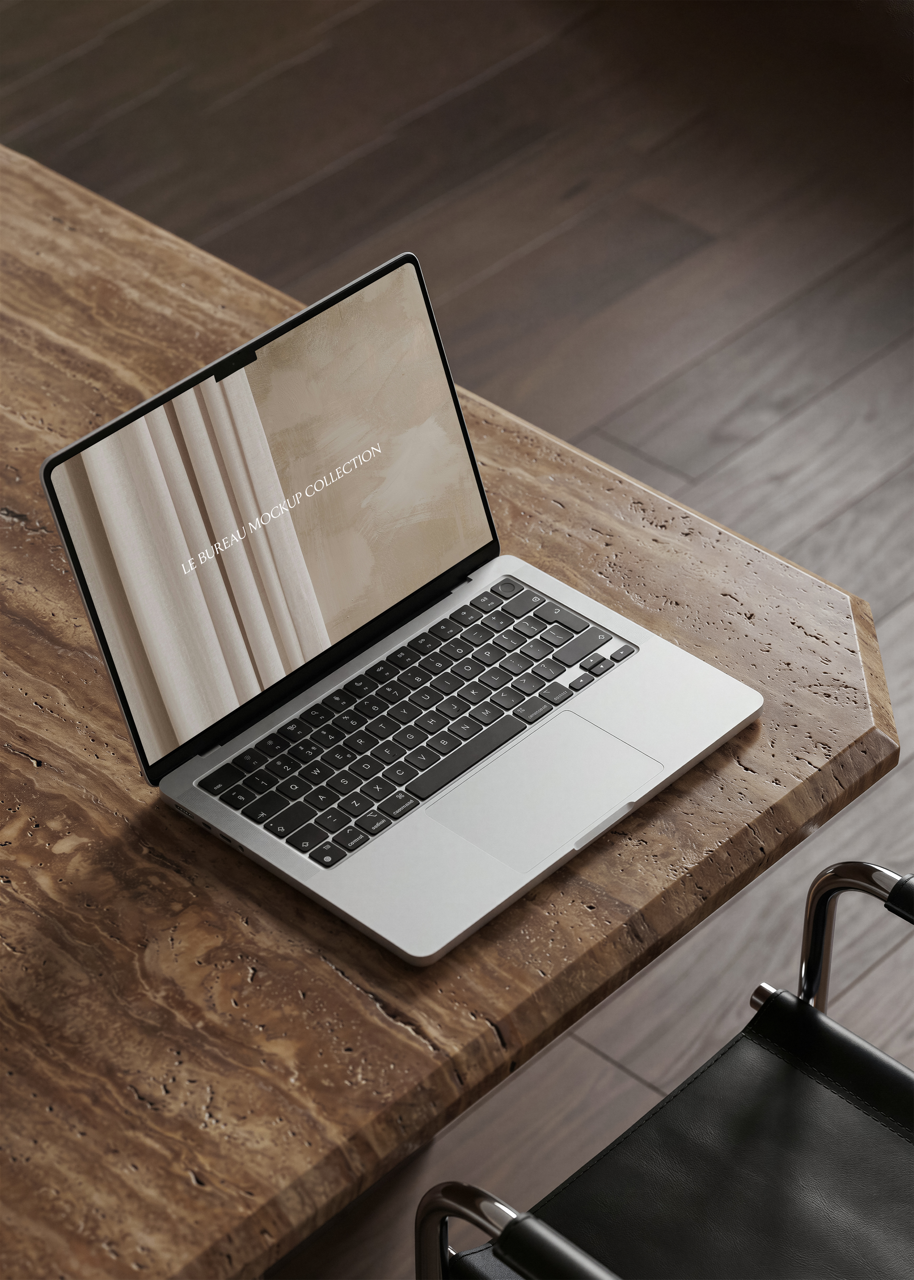 MacBook mockup displaying Le Bureau editorial from overhead on travertine desk, dark oak herringbone floor backdrop