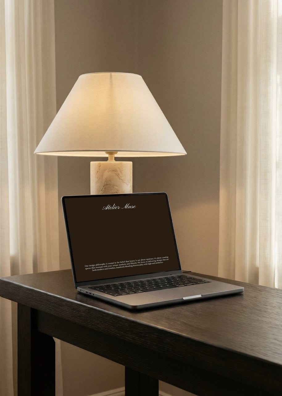 Laptop on a wooden desk with a lamp and curtains in the background