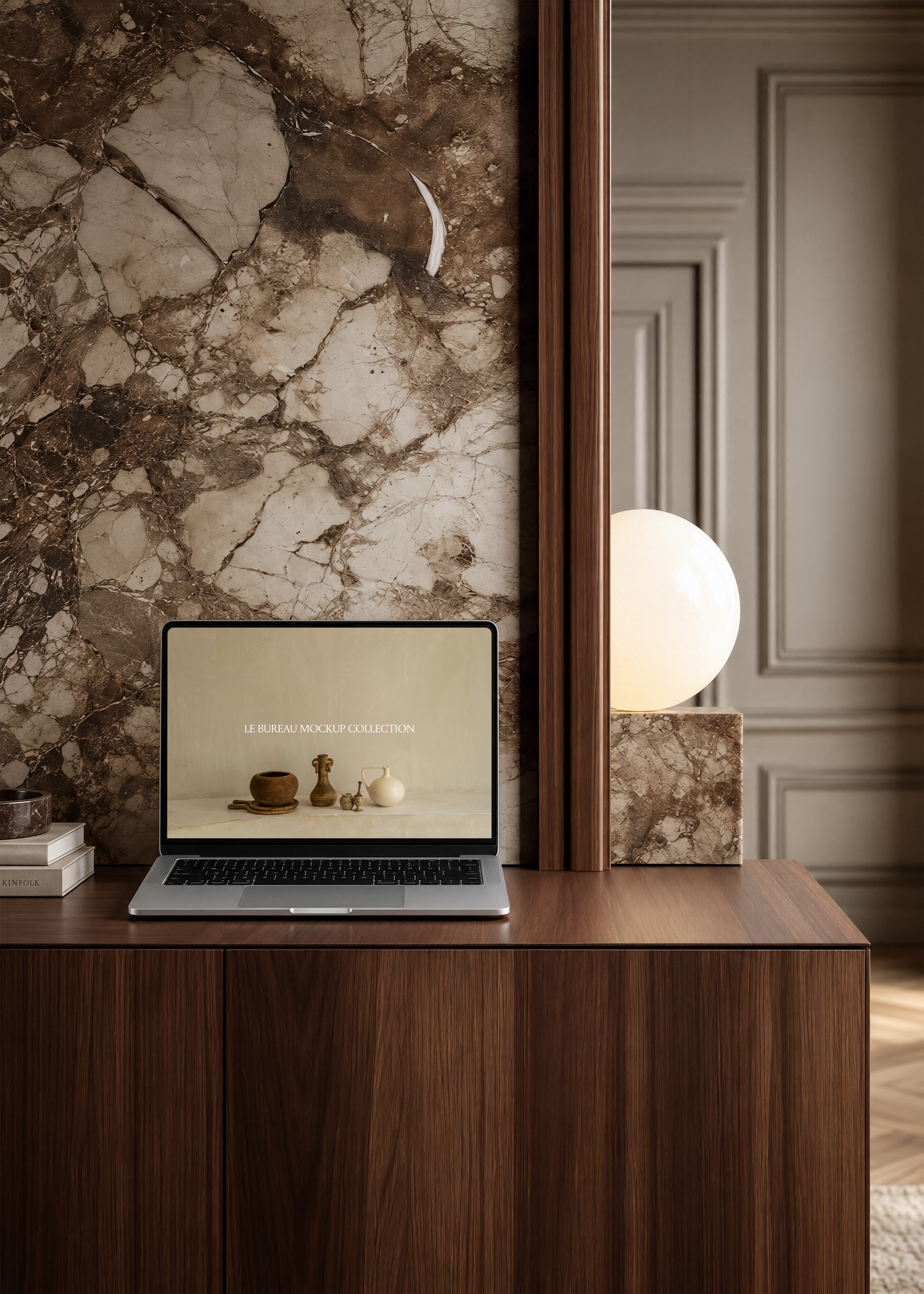 MacBook mockup displaying Le Bureau editorial on walnut desk, stone globe lamp and veined marble panel background