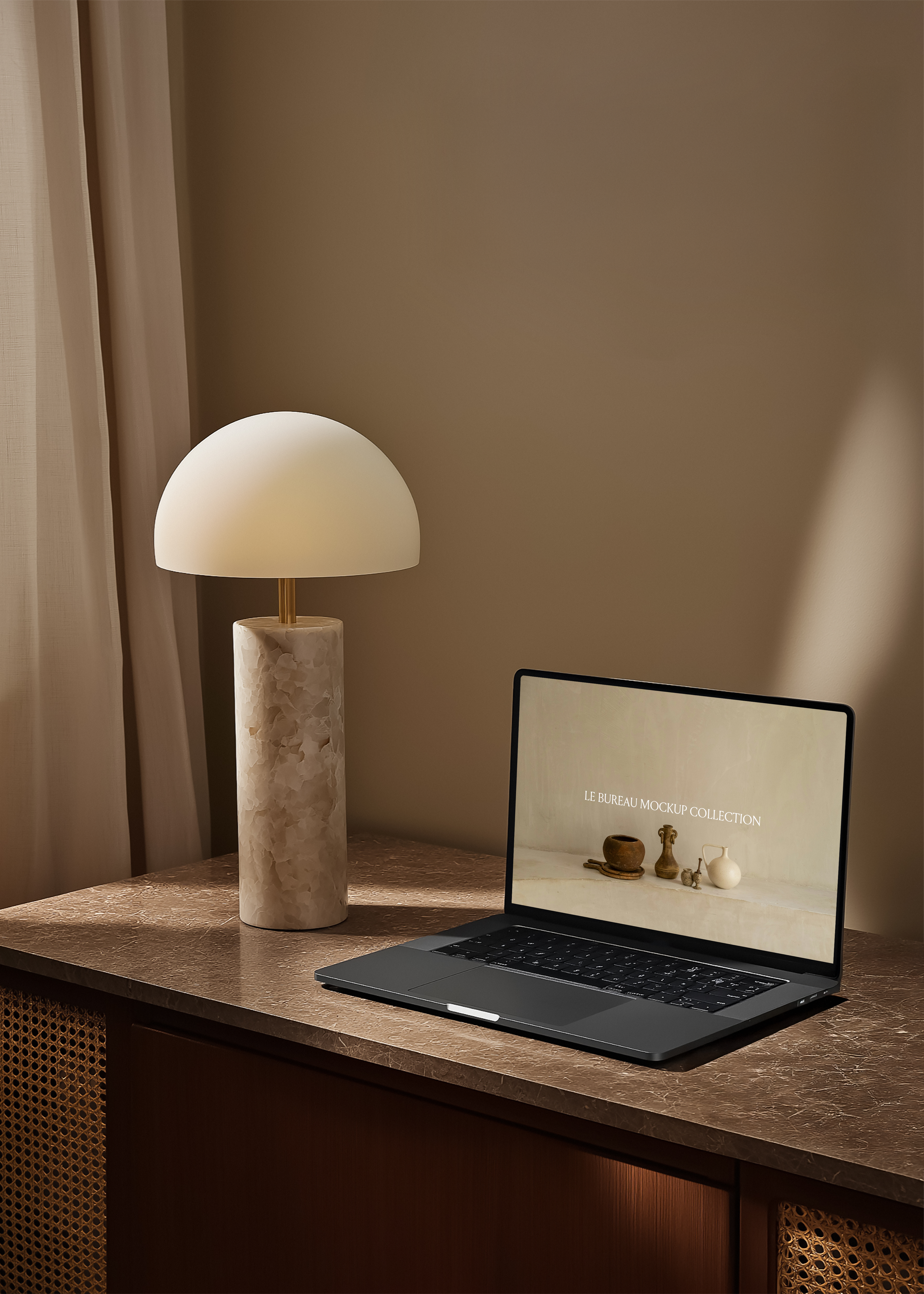 MacBook mockup displaying Le Bureau editorial on marble desk, alabaster dome lamp and rattan cabinet warm interior
