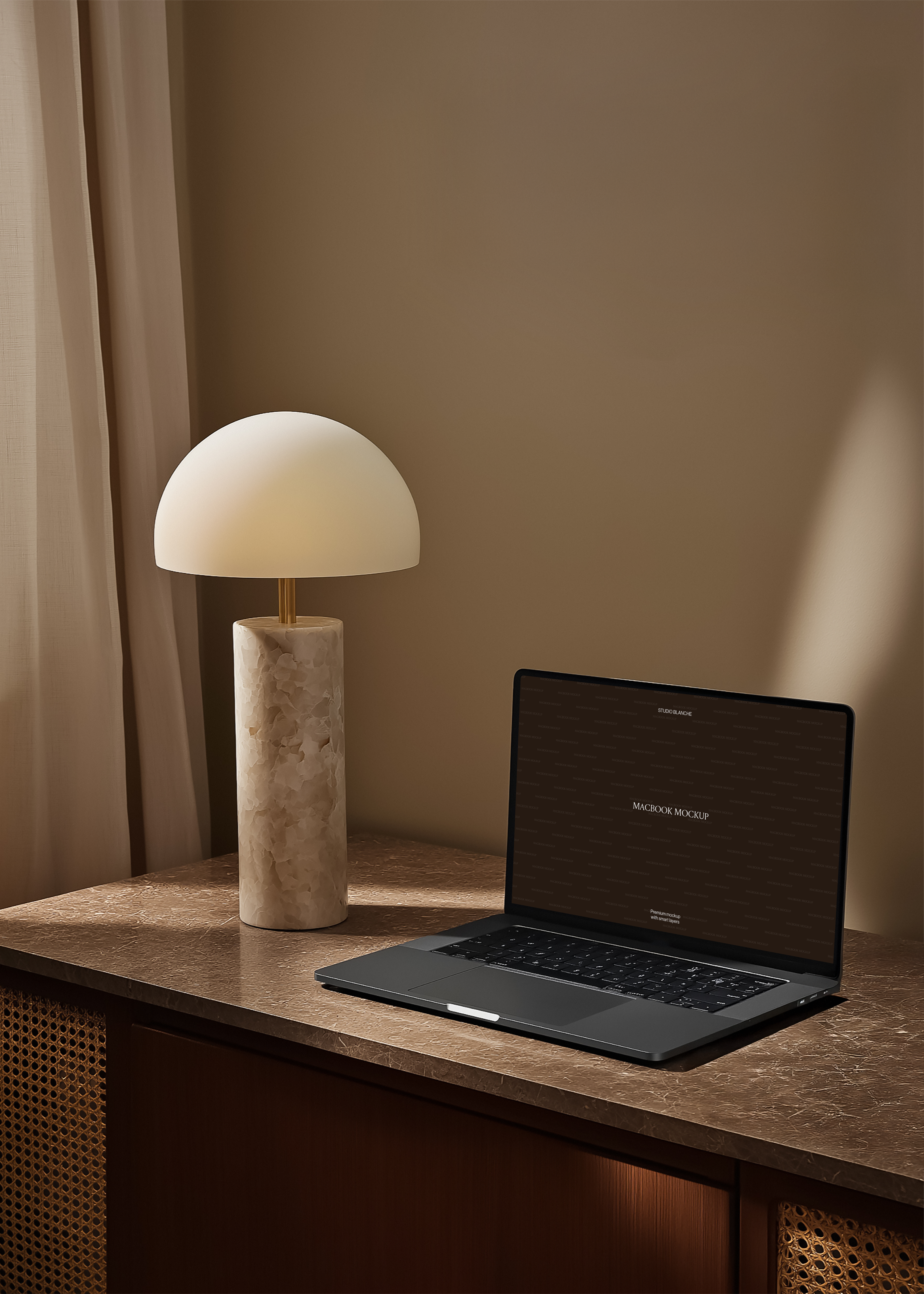 MacBook mockup on brown marble desk beside alabaster dome lamp, rattan cabinetry and warm caramel wall backdrop