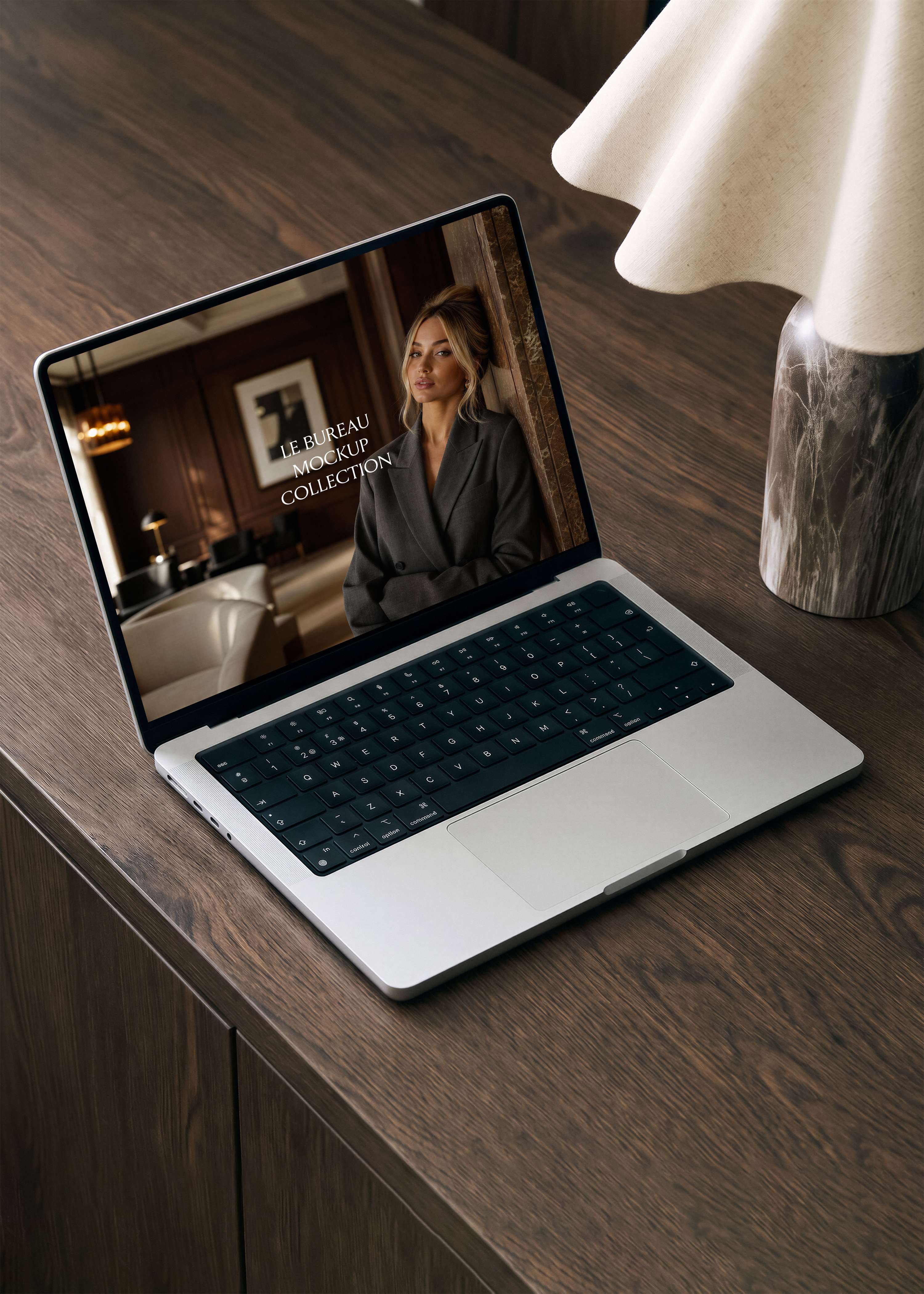 MacBook mockup on walnut desk displaying Le Bureau editorial image, dark warm office styling