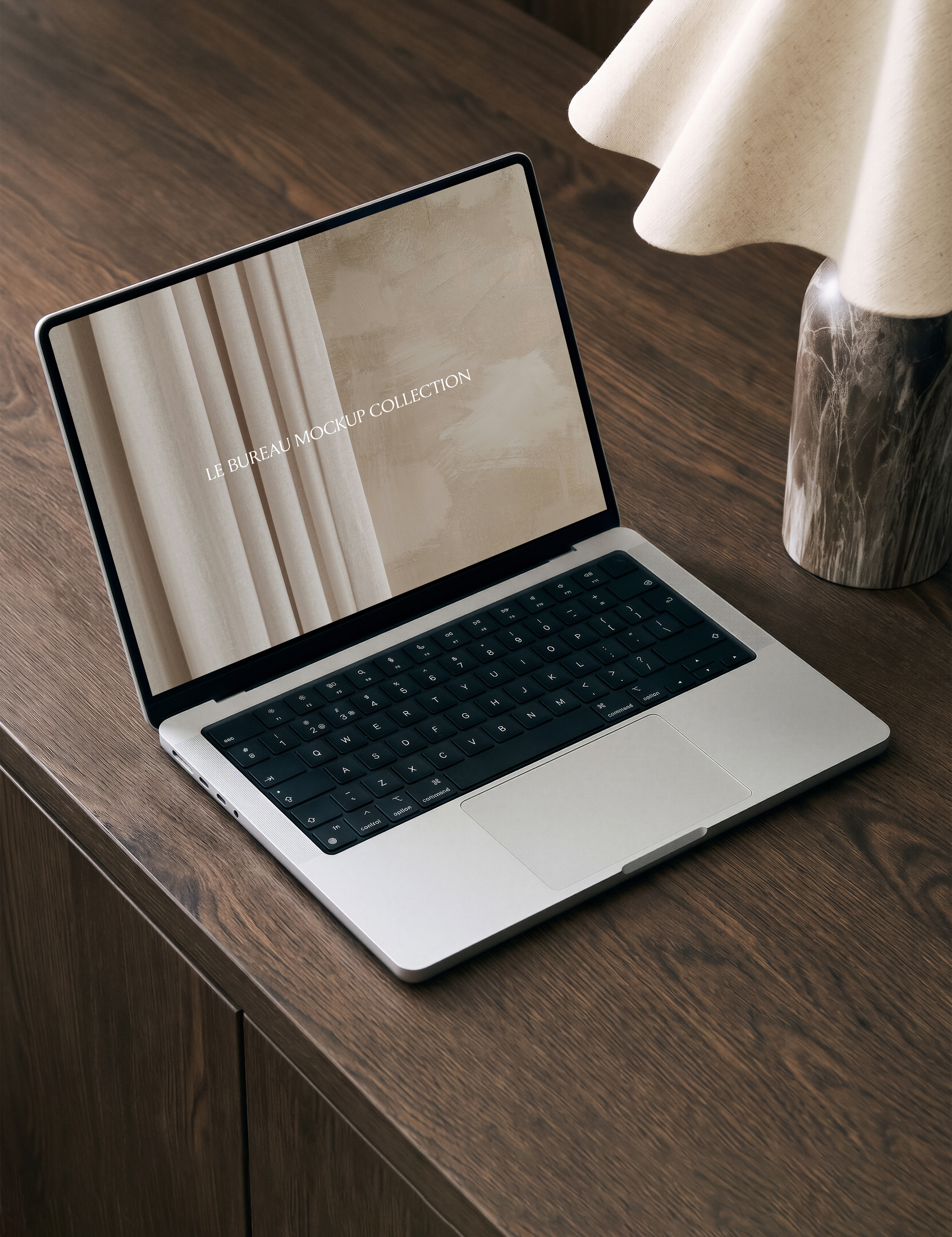 MacBook mockup on walnut desk displaying Le Bureau editorial image, dark warm office styling