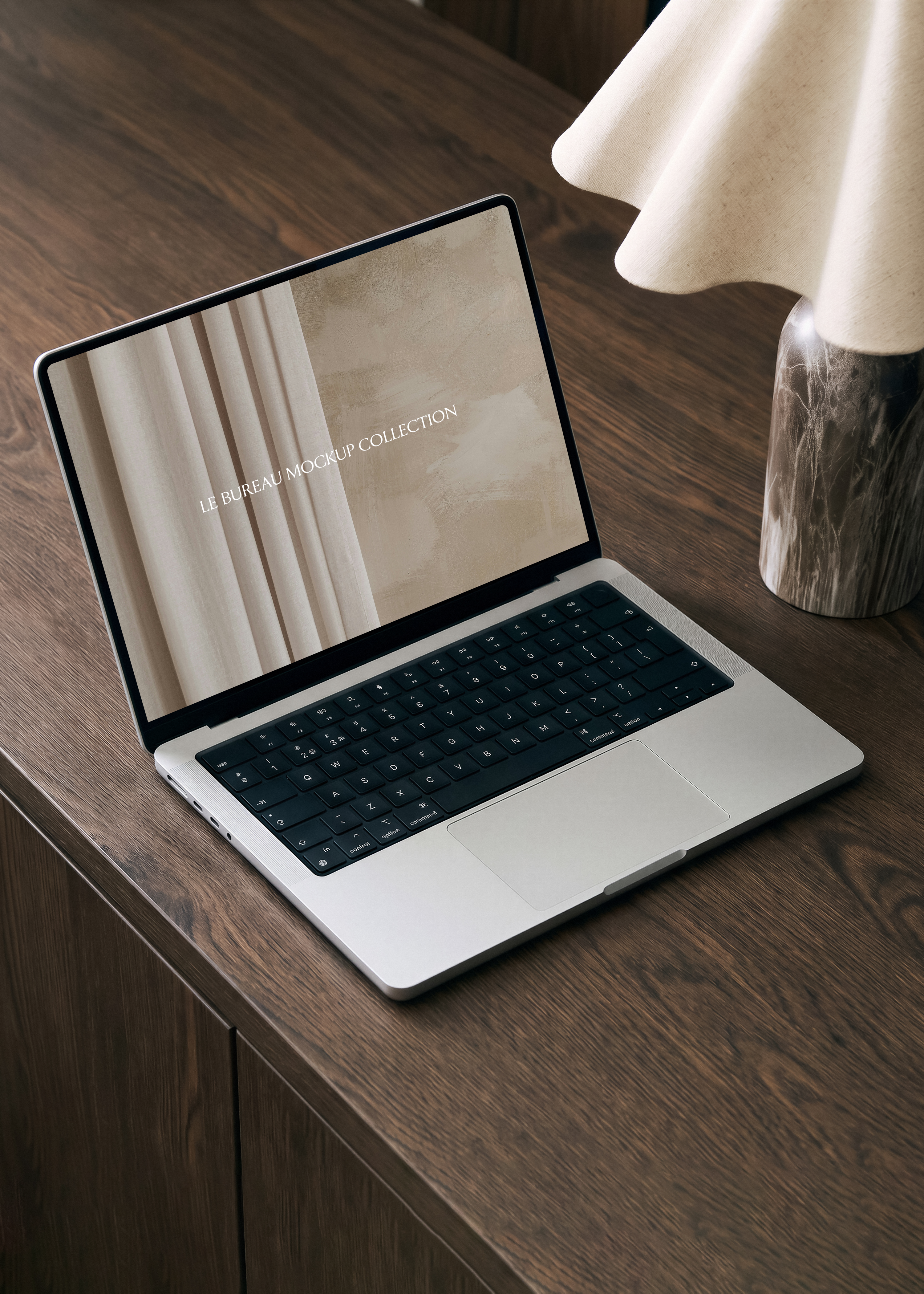 MacBook mockup on walnut desk displaying Le Bureau editorial image, dark warm office styling