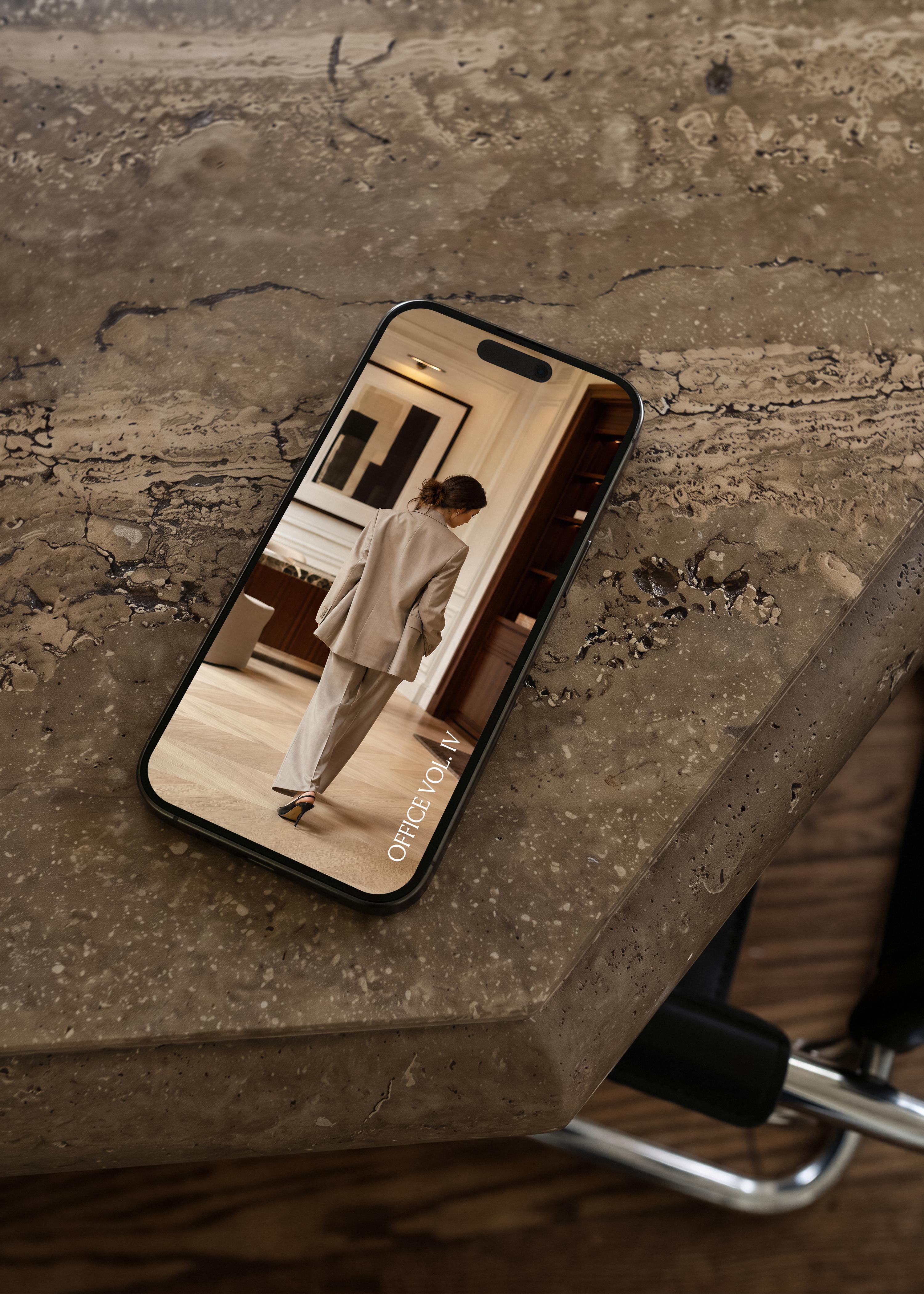 iPhone on travertine surface showing stone-suited woman in plaster-moulded interior, Office Vol. IV editorial stock mockup

