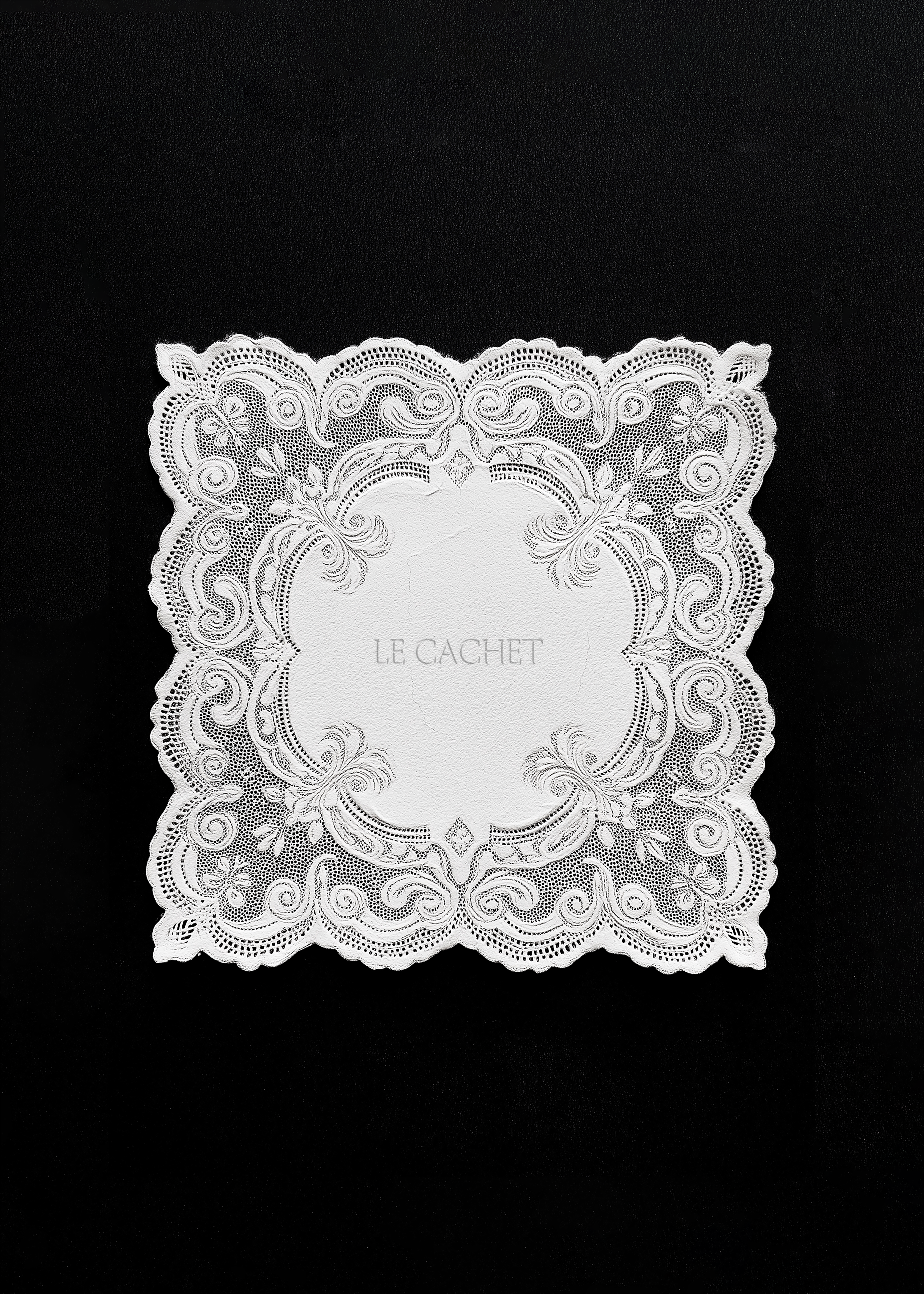 Square scalloped lace napkin mockup on black cloth, baroque scrollwork border around a blank oval centre