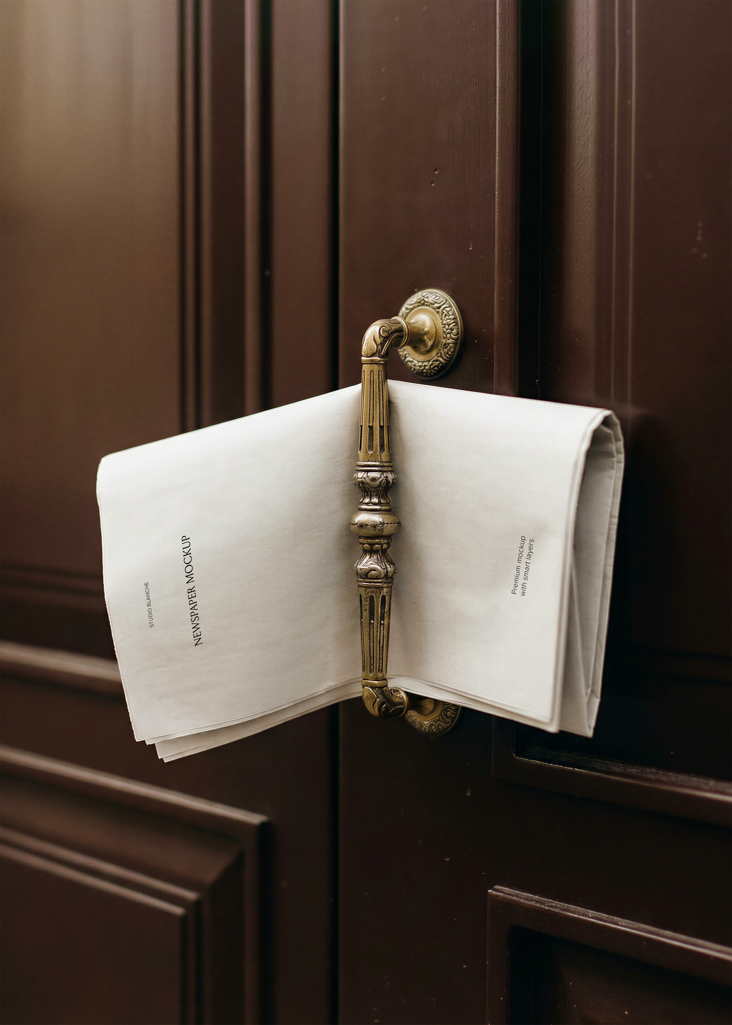 Folded newspaper mockup draped over an ornate brass door handle on a dark wood panelled door