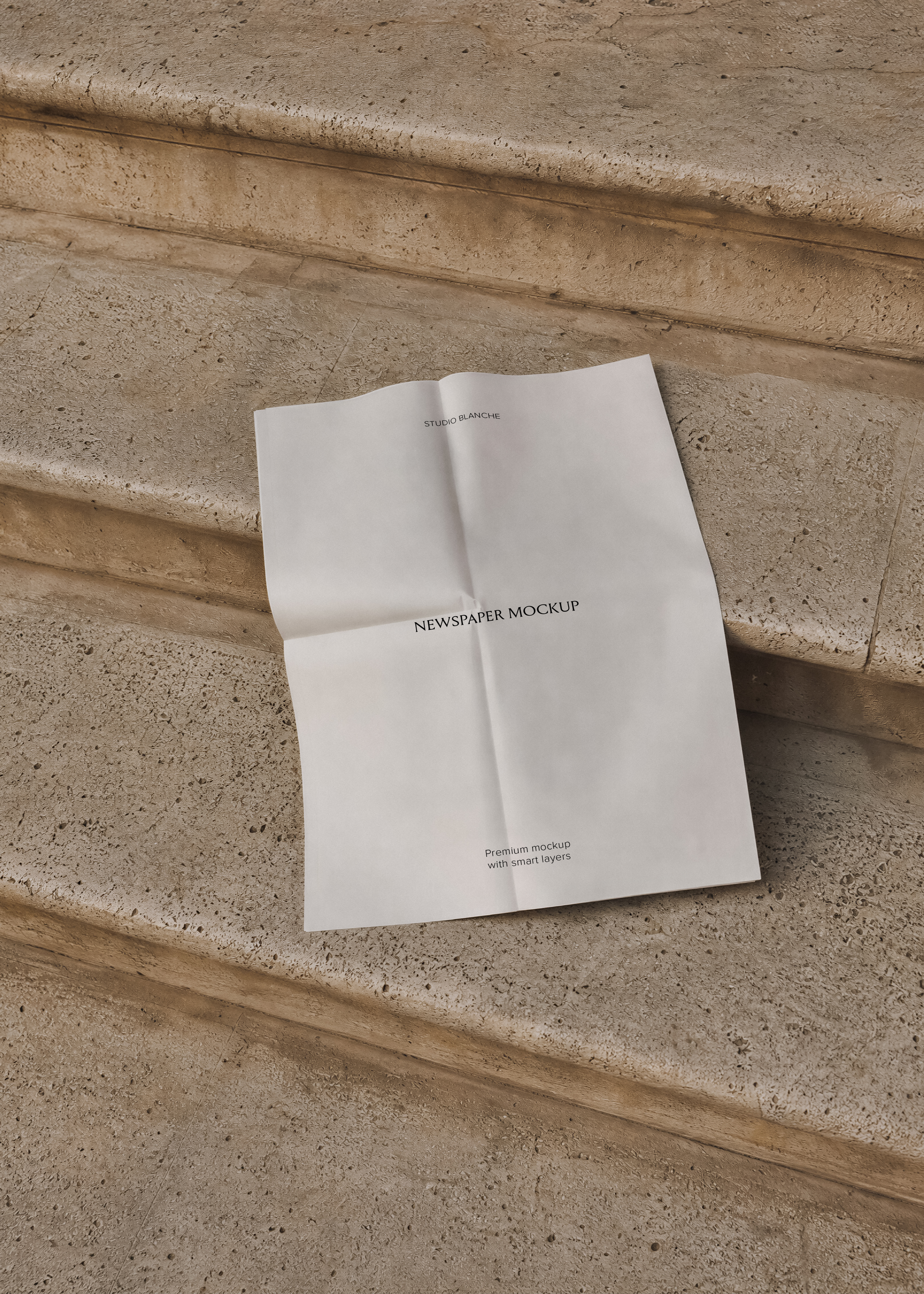 Folded newspaper mockup resting on weathered beige stone steps with visible crease lines and fold marks