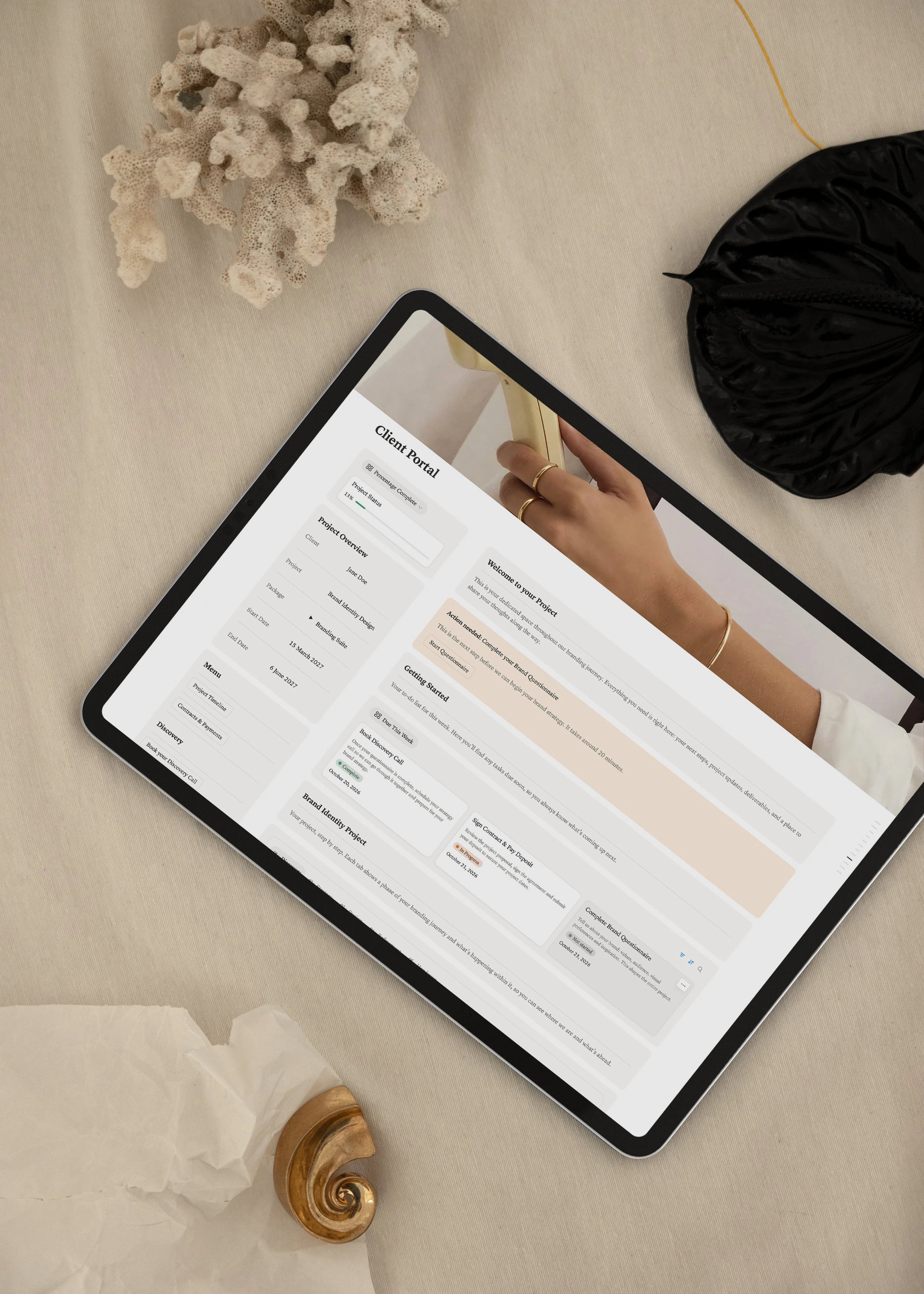 Notion brand identity client portal dashboard on an iPad, showing project progress, overview, menu and weekly tasks, styled with coral and a gold shell on linen.