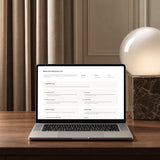 Notion client portal Book Your Discovery Call page on a laptop, showing call details and what to cover, on a walnut desk beside a glowing globe lamp.