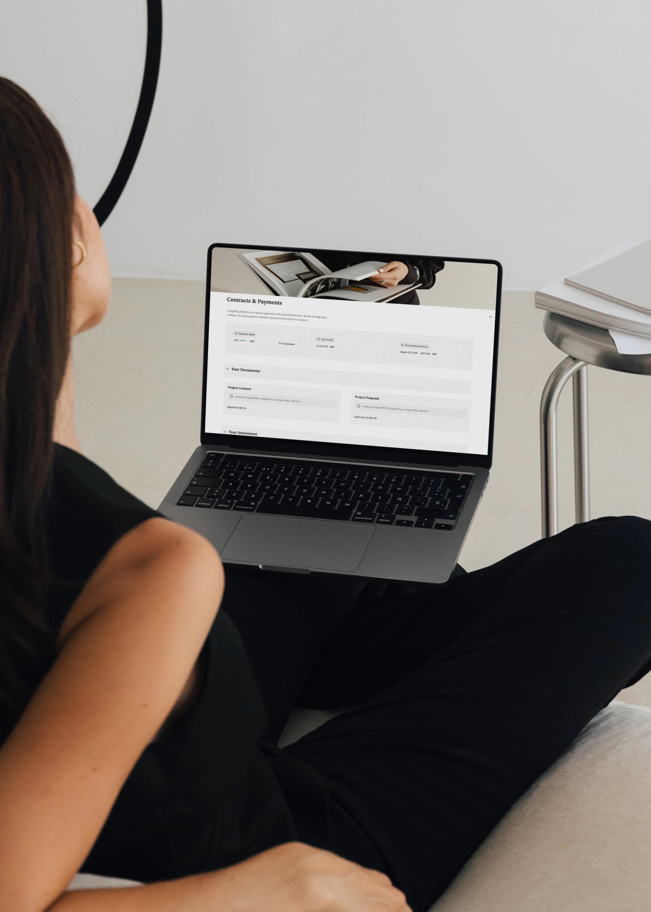 Woman viewing the Notion client portal Contracts & Payments page on a laptop, showing payments made, amount paid, next payment due and project documents.
