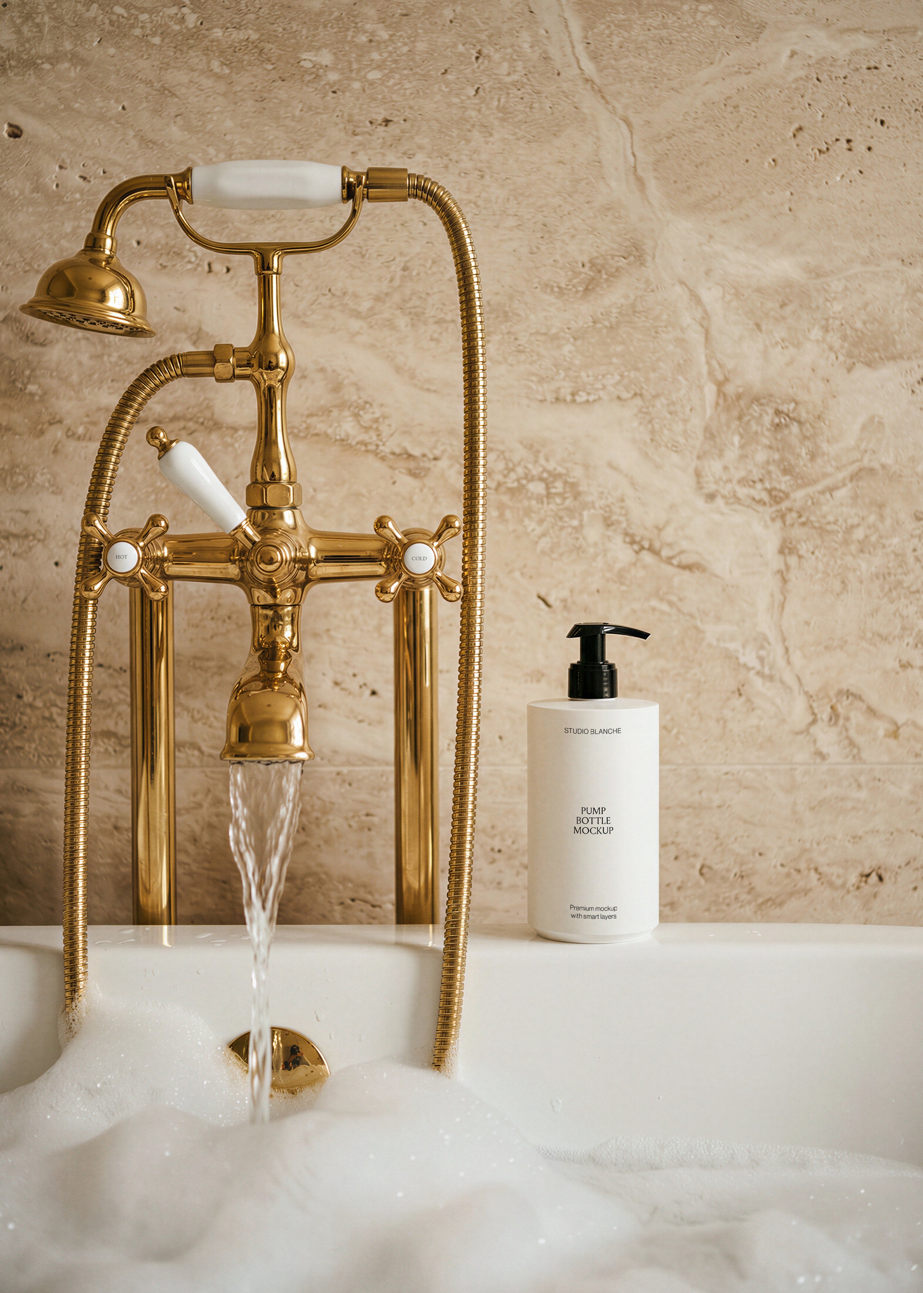 Pump bottle mockup on foam-filled bath rim with ornate brass mixer tap and travertine wall, warm light, styled bath scene