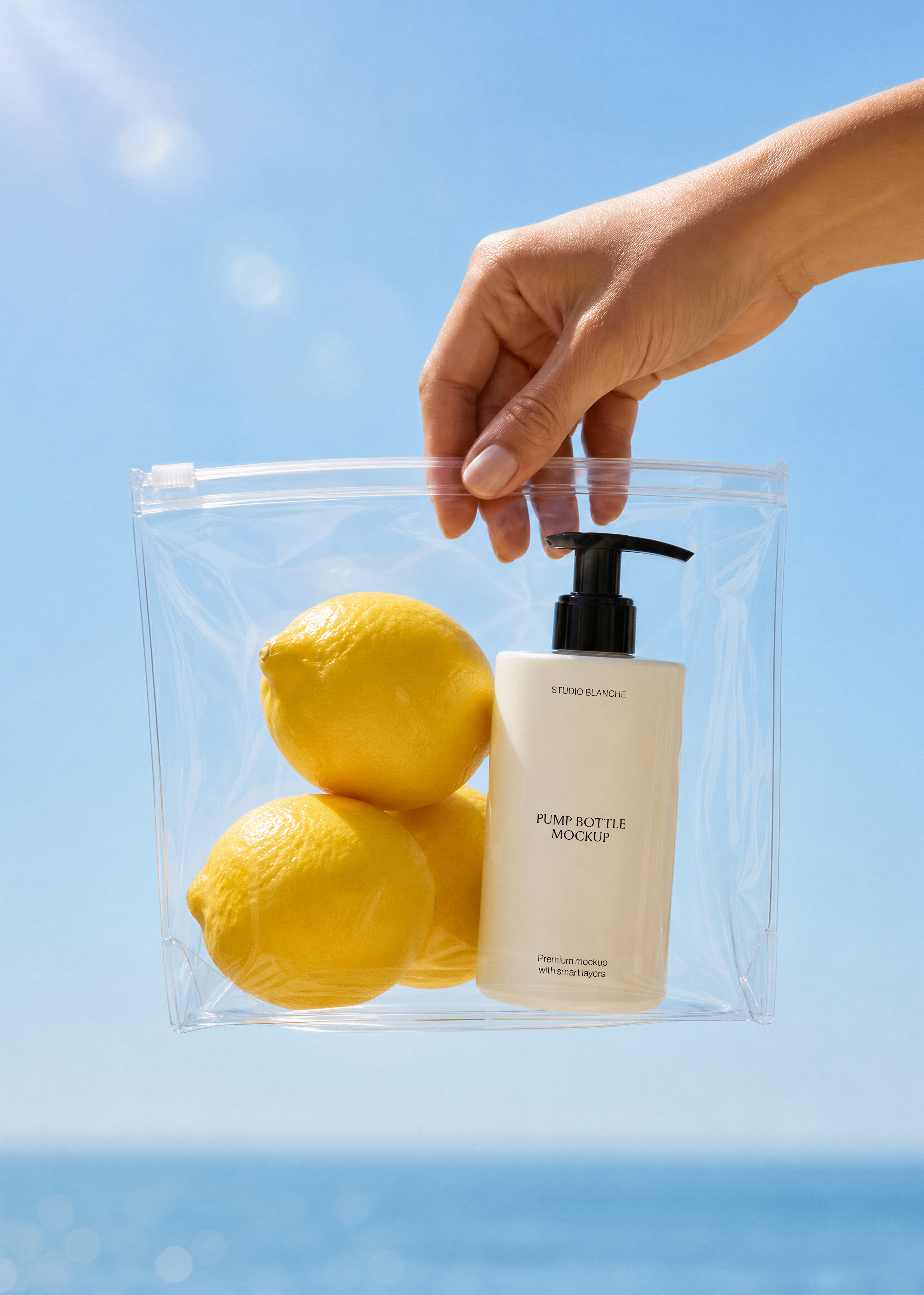 Close view of a white pump bottle label beside yellow lemons in a transparent bag, blue sky and sea, coastal scene