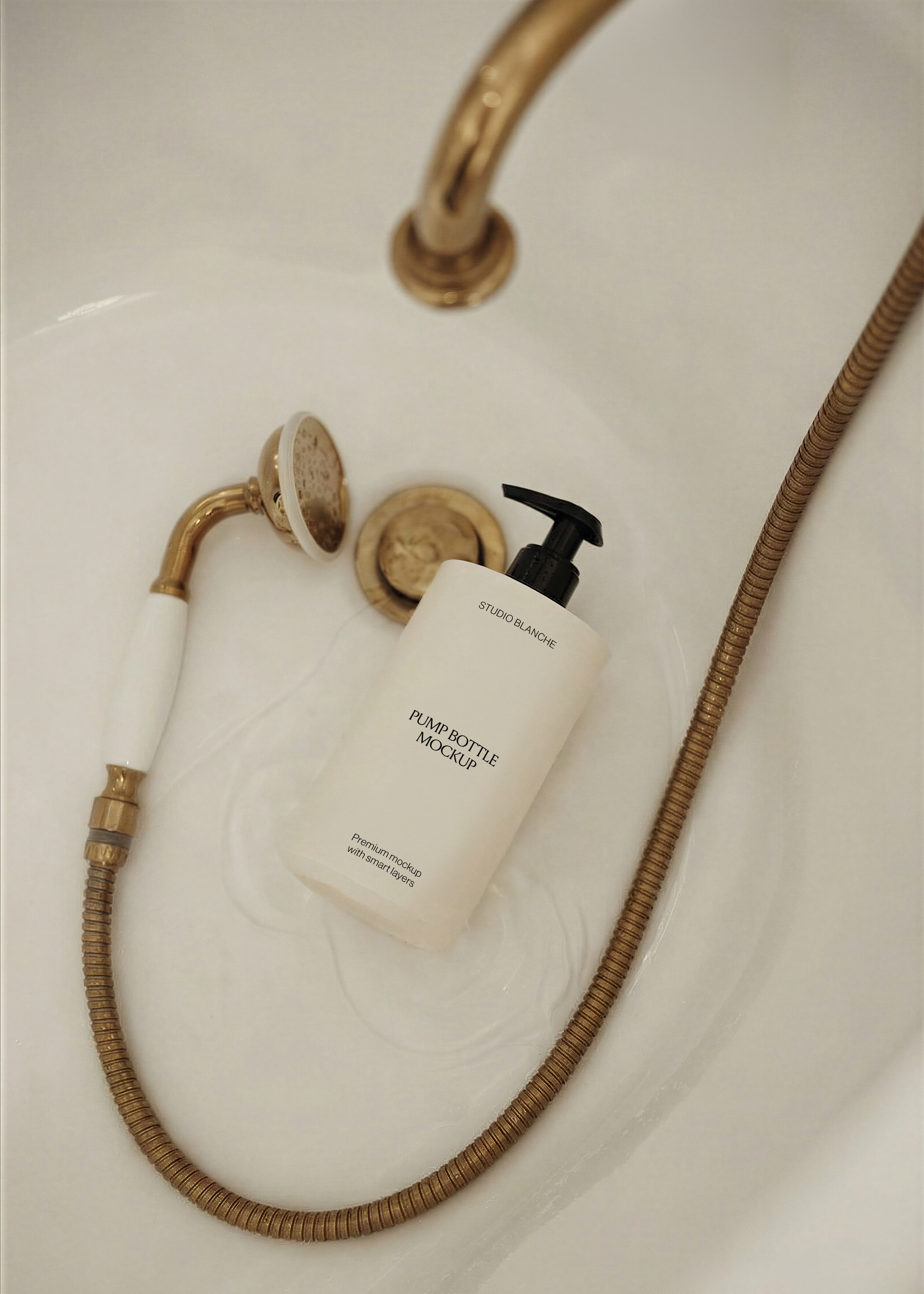 Close view of white pump bottle mockup with minimal black label, gold handheld shower head, warm editorial styling