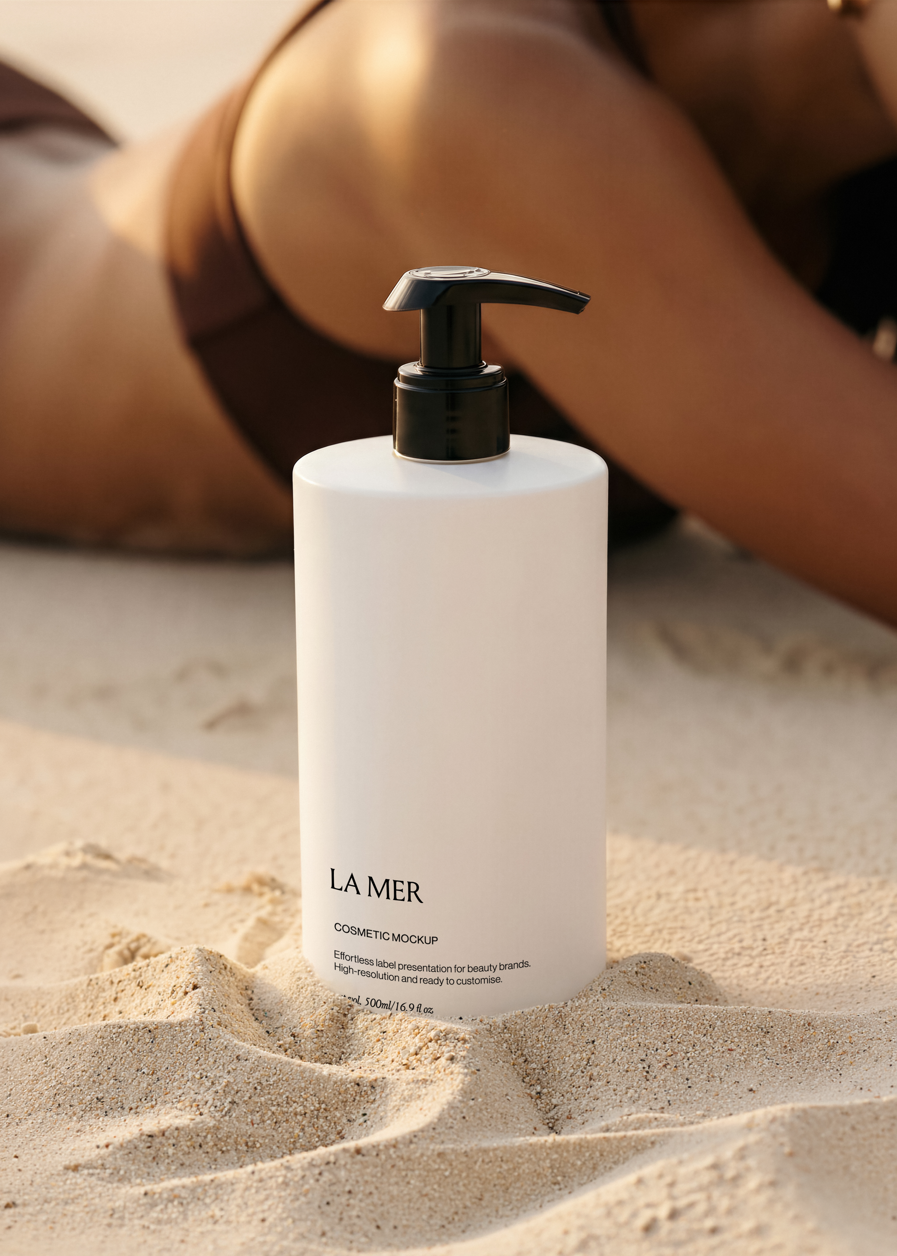 White cosmetic pump bottle mockup standing in sand on a sunlit beach, blank label area, warm golden tones, editorial styling