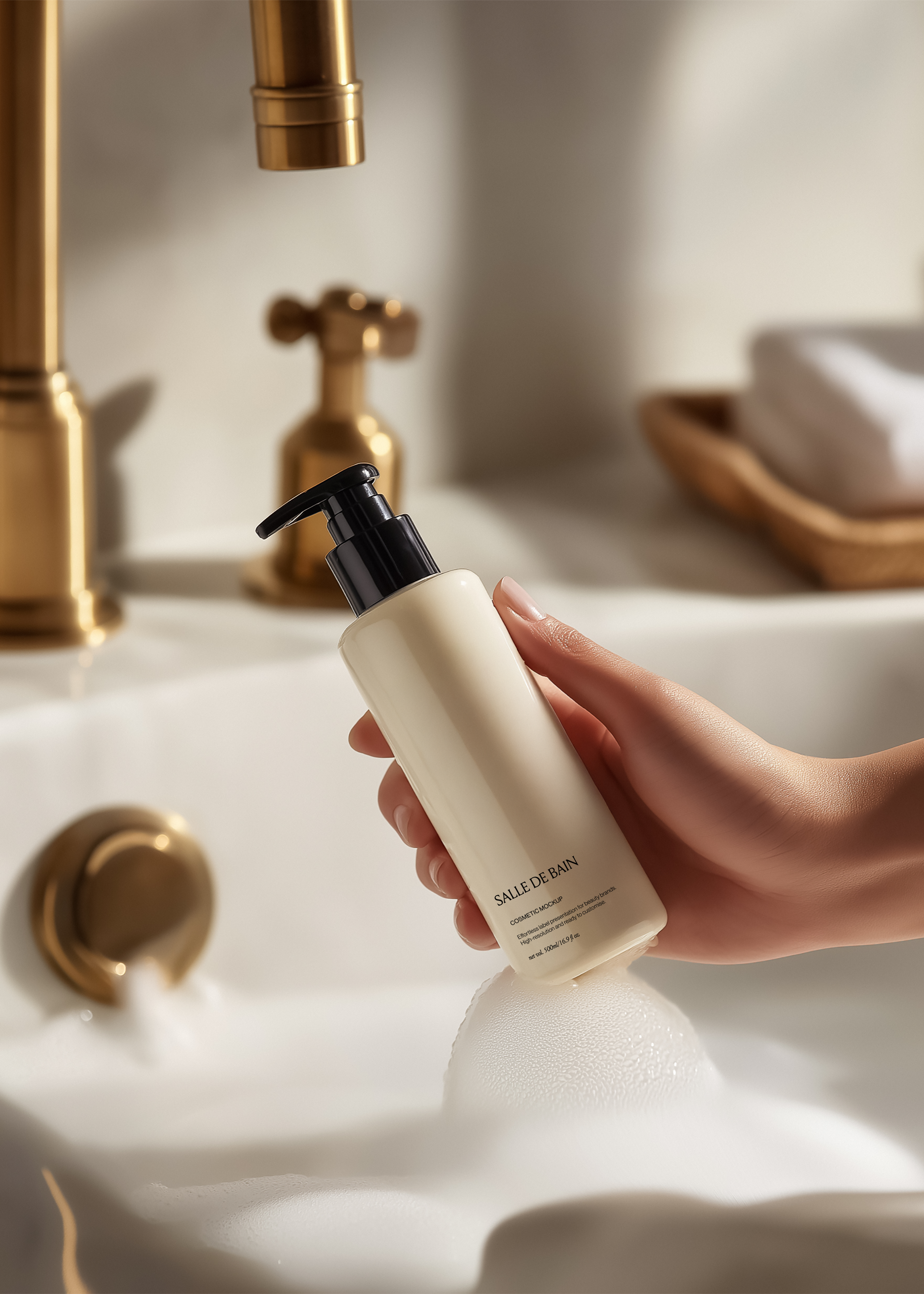 Cream cosmetic pump bottle with black dispenser held over a white basin with running brass tap and soap dish behind