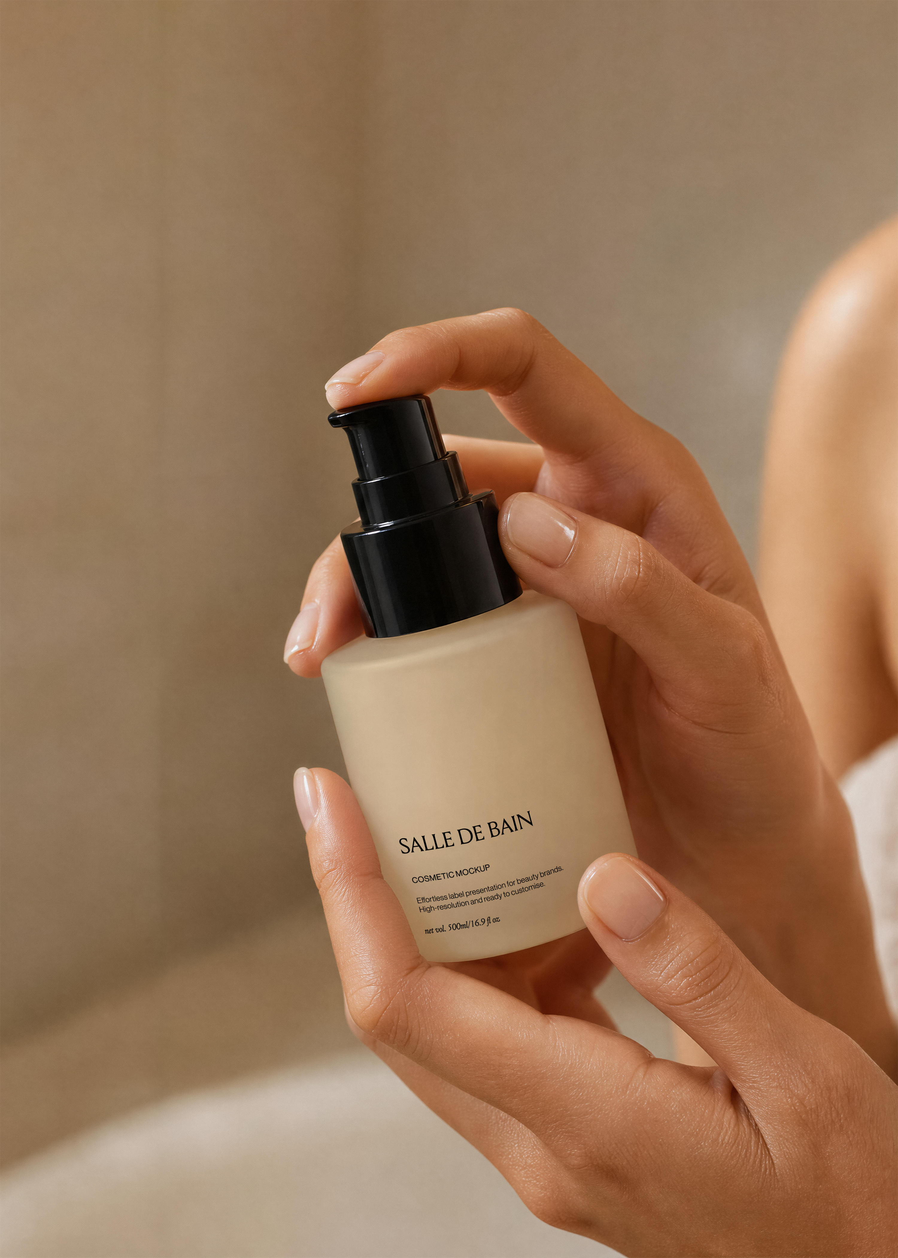 Frosted glass pump bottle mockup with glossy black pump held in two hands against a warm sandstone bathroom backdrop
