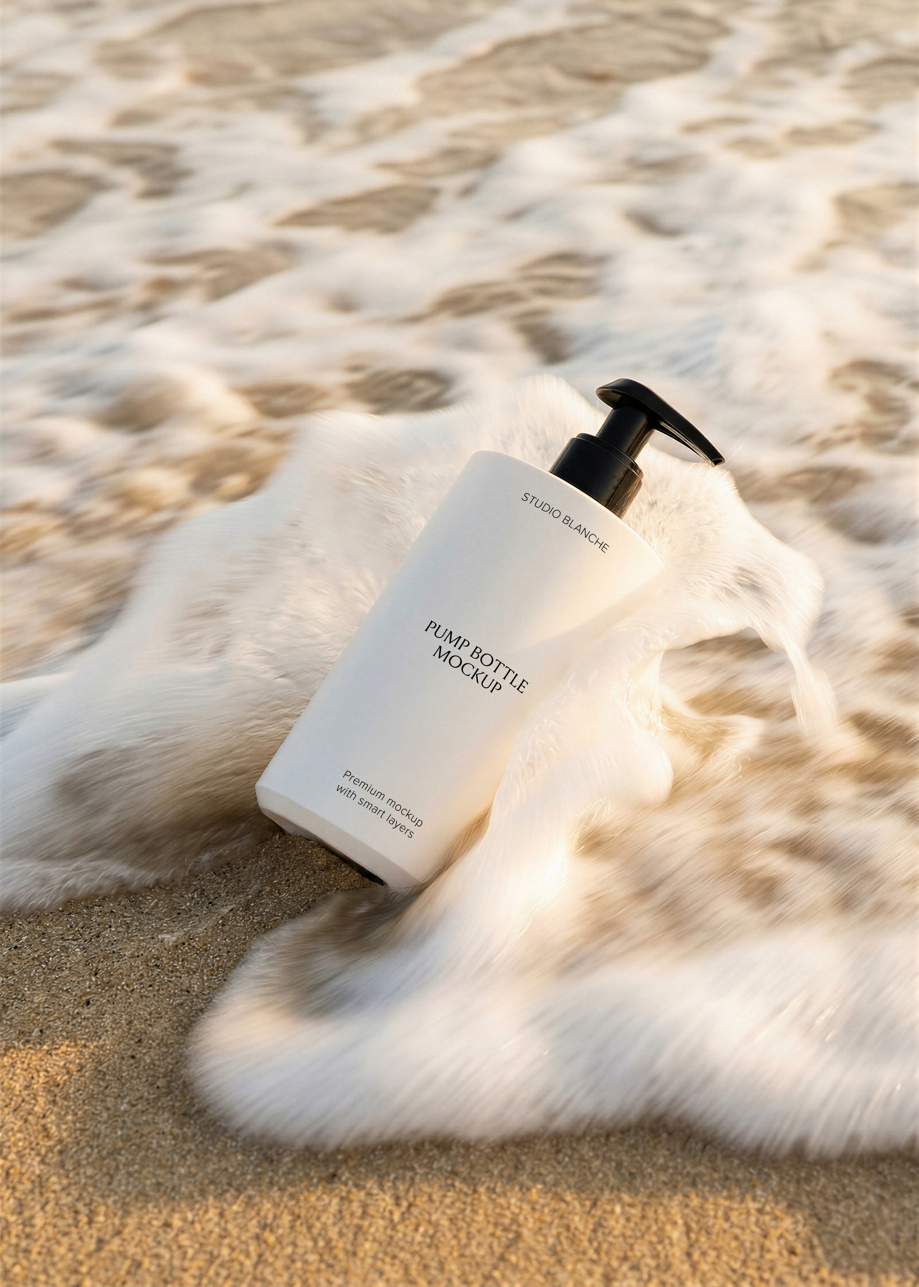 Blank white flat pump bottle with black dispenser tilted in wet sand surrounded by a foamy breaking wave in golden light, from Studio Blanche