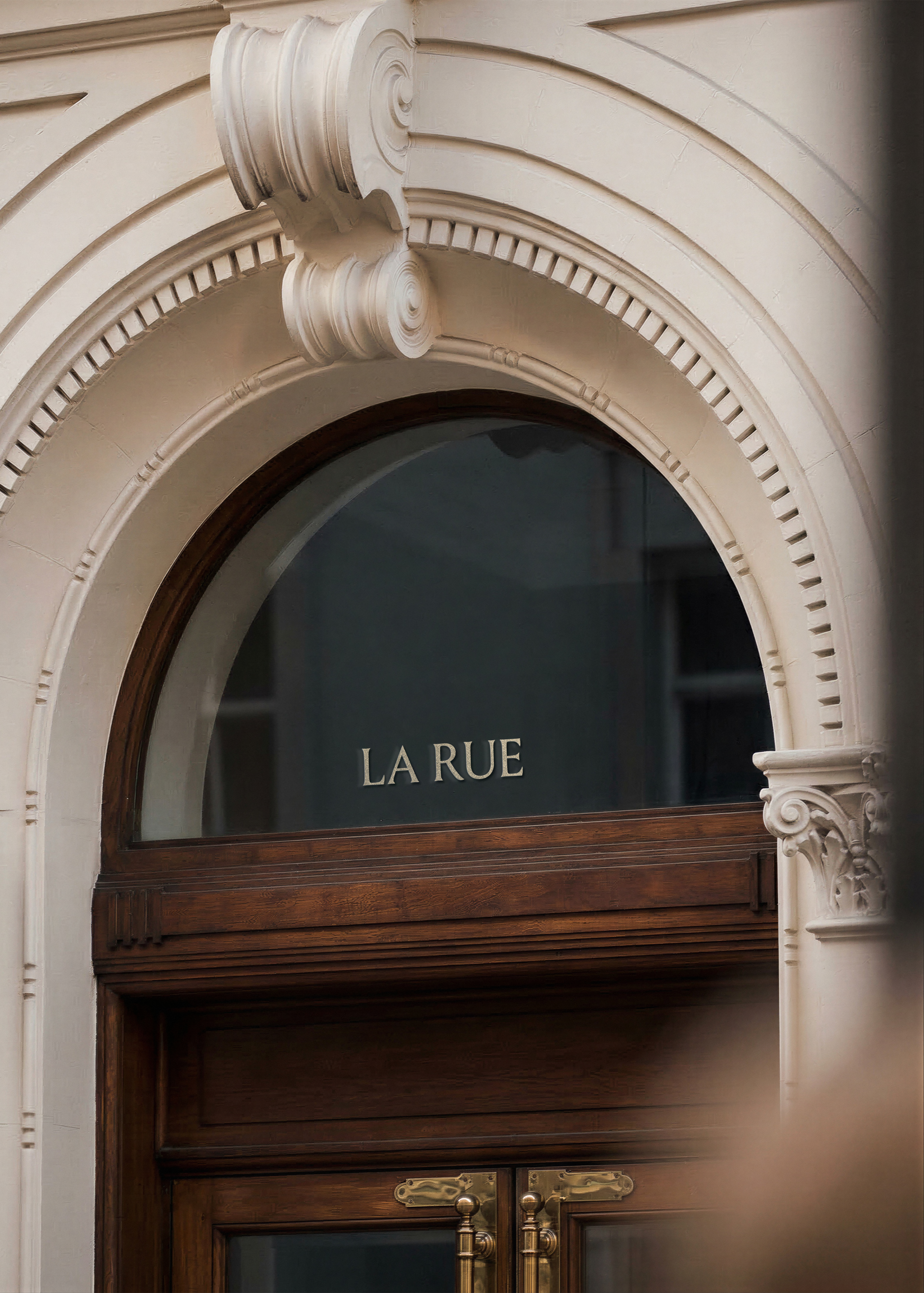 Shopfront window mockup with script brand name in ornate arched doorway with dark wood and brass hardware, from Studio Blanche