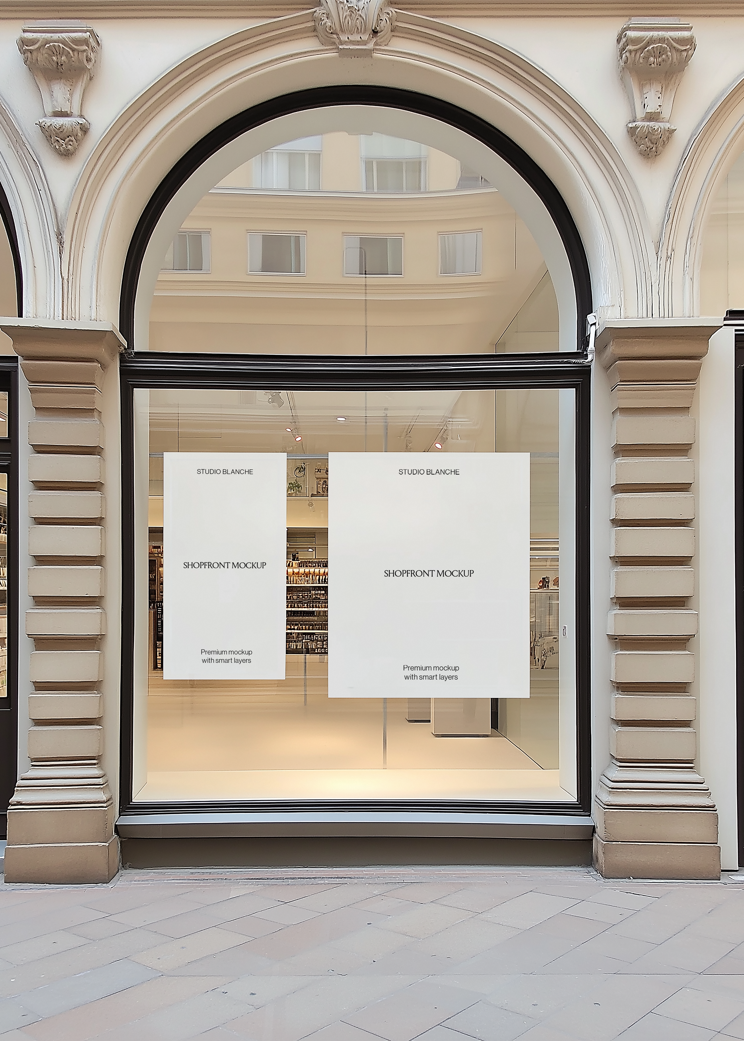 Retail window display mockup on a classic stone facade with black frame, carved columns and pale paving underfoot