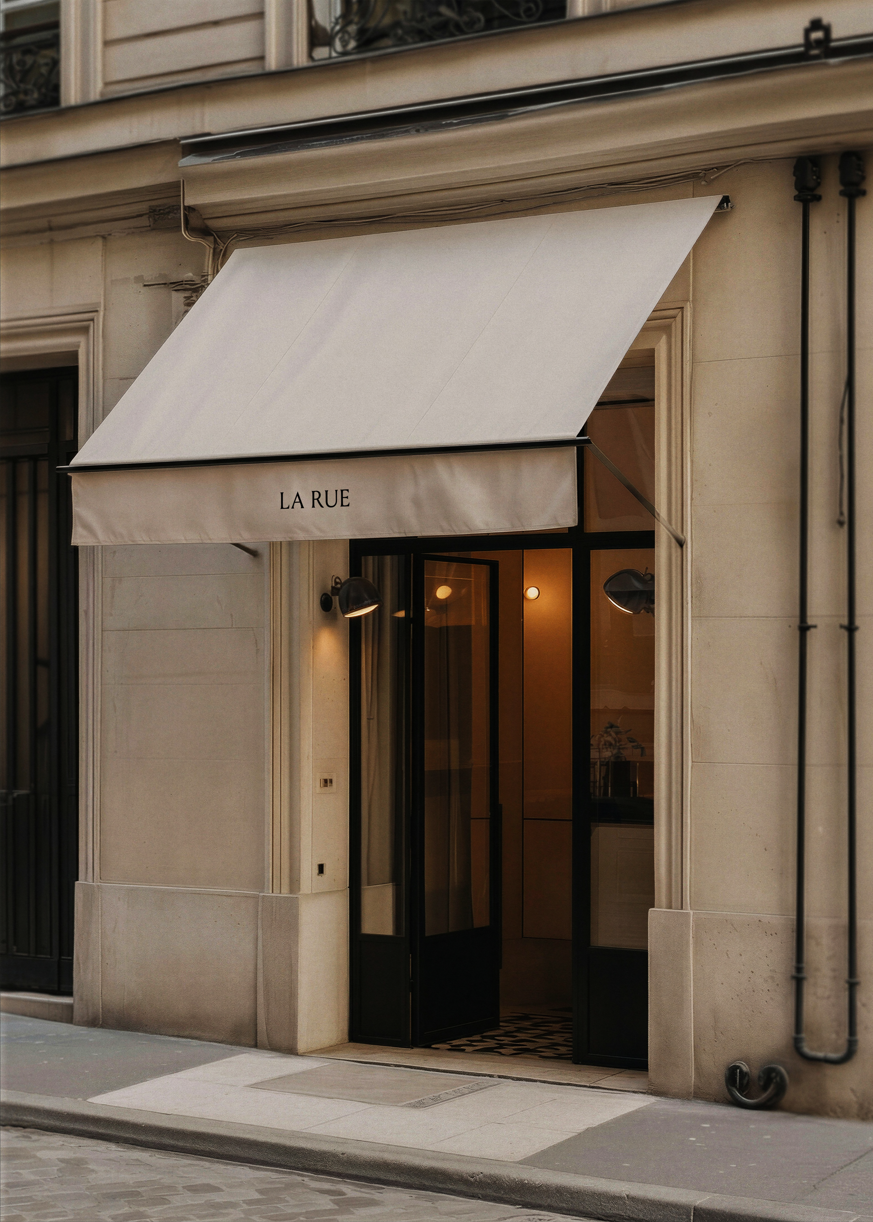 Shopfront awning mockup displaying brand name in elegant serif type on a Parisian boutique exterior with warm glowing doorway, from Studio Blanche