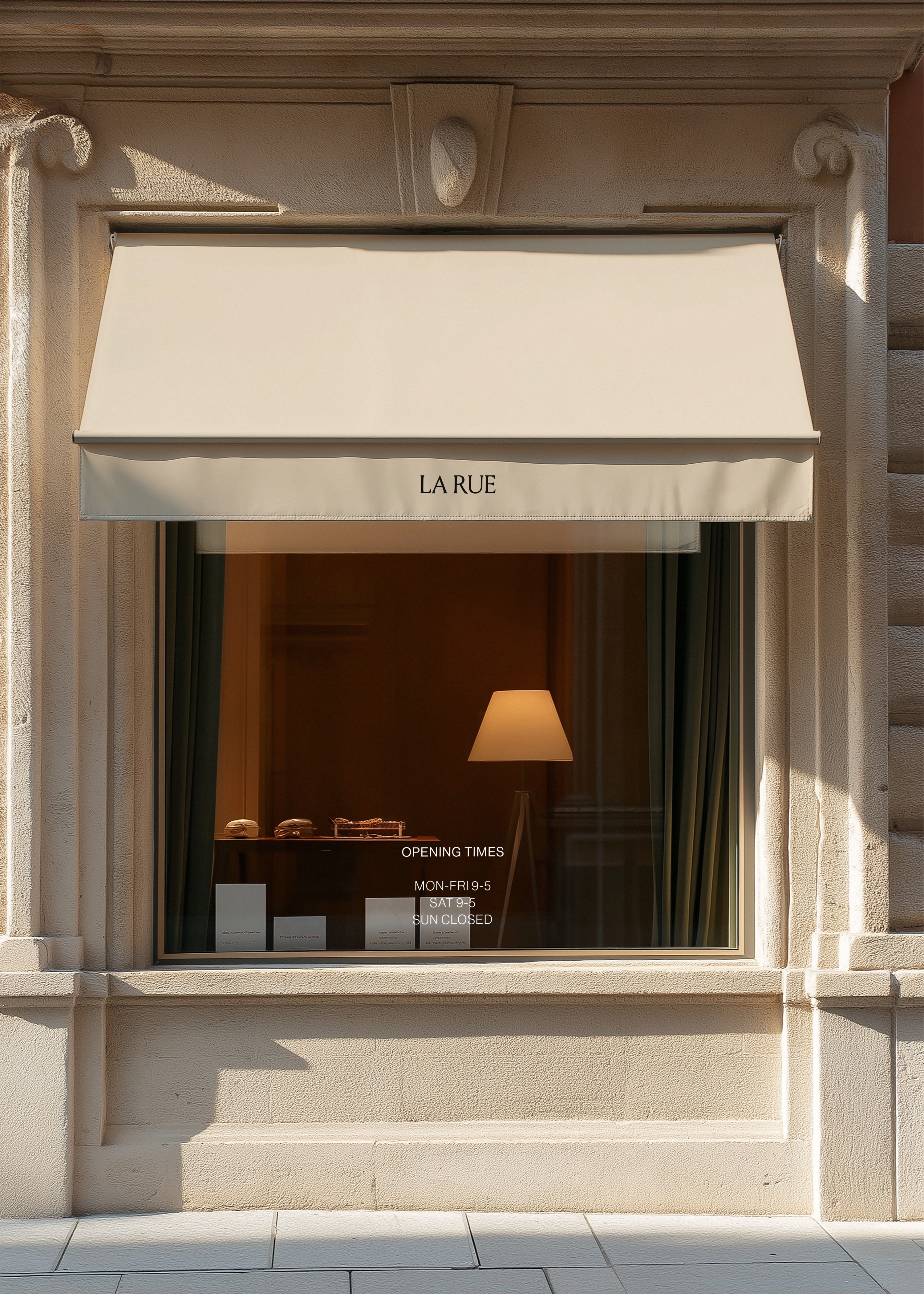 Shopfront mockup with cream canopy awning reading LA RUE over a warm lamplit window display on a stone facade