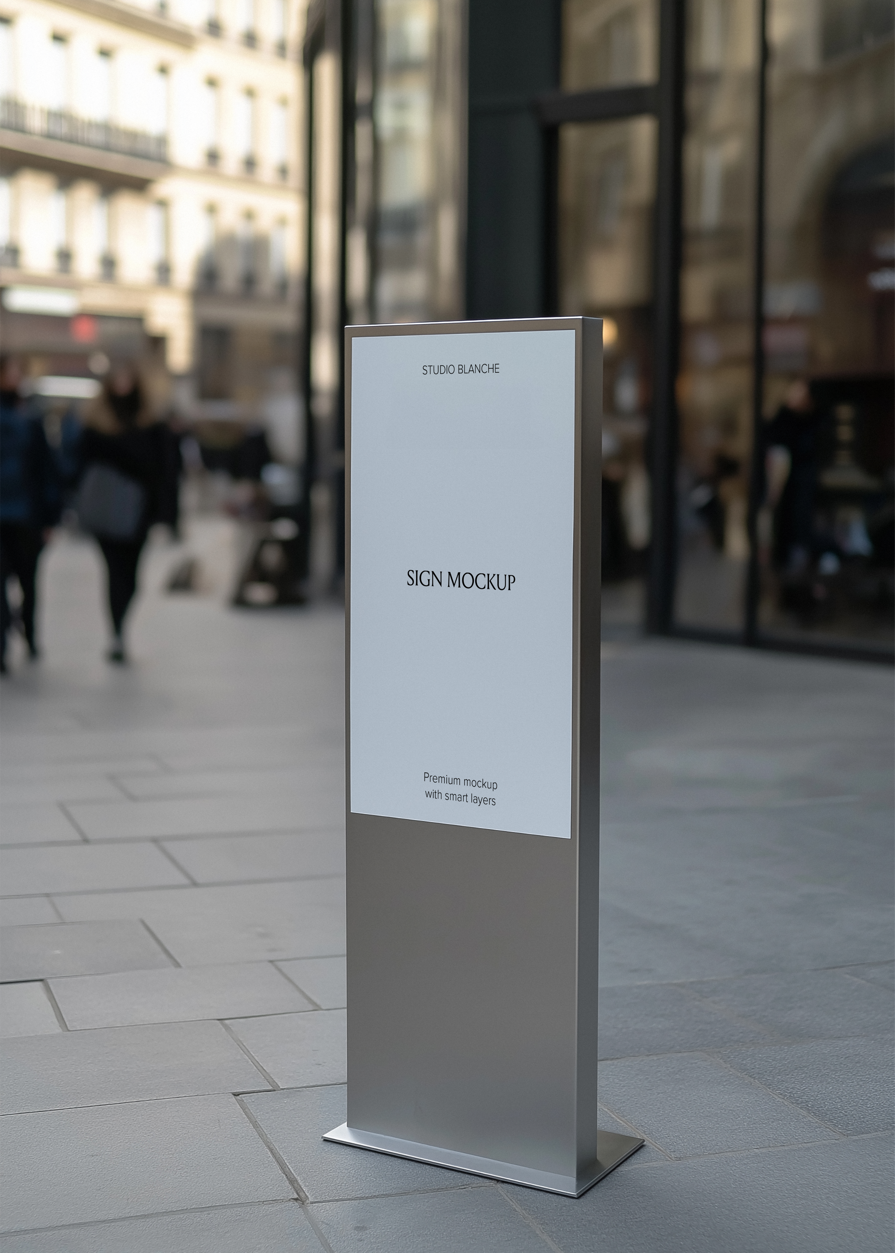 Freestanding silver totem sign mockup on stone pavement, glass shopfront and blurred Parisian street scene behind